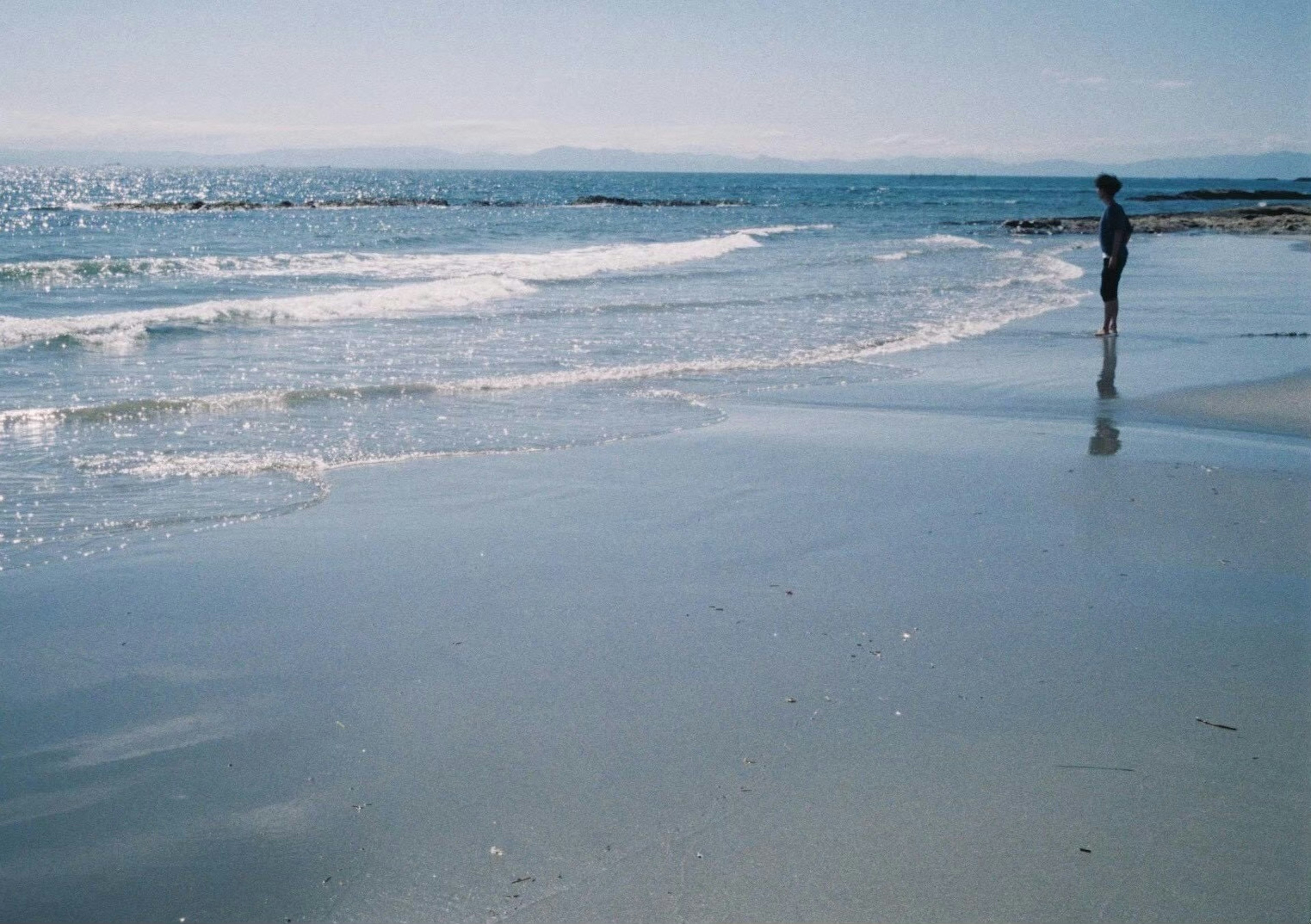 Person schaut auf die Wellen an einem ruhigen Strand