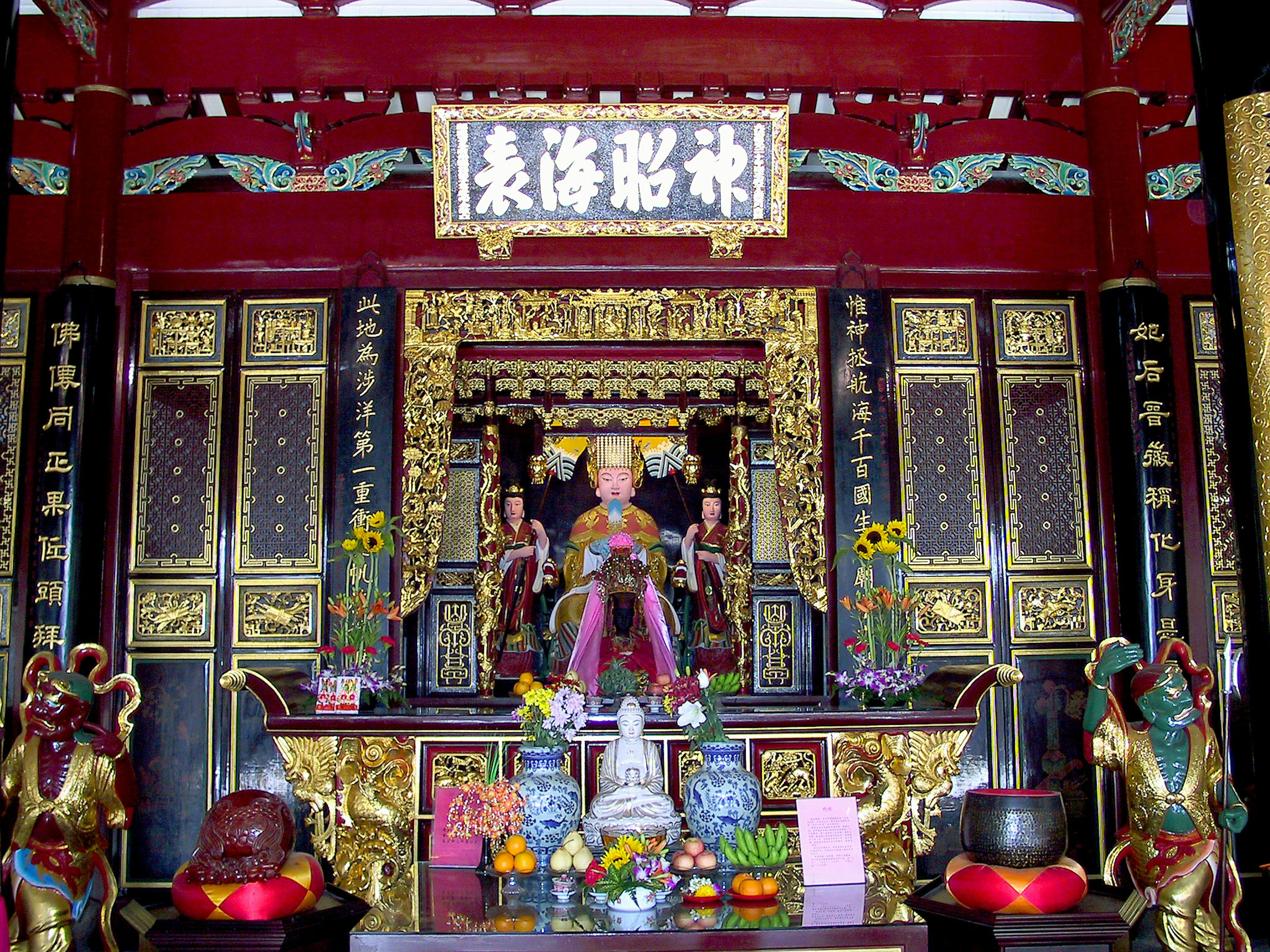 Colorful altar with intricate decorations featuring a central Buddha statue and surrounding deities