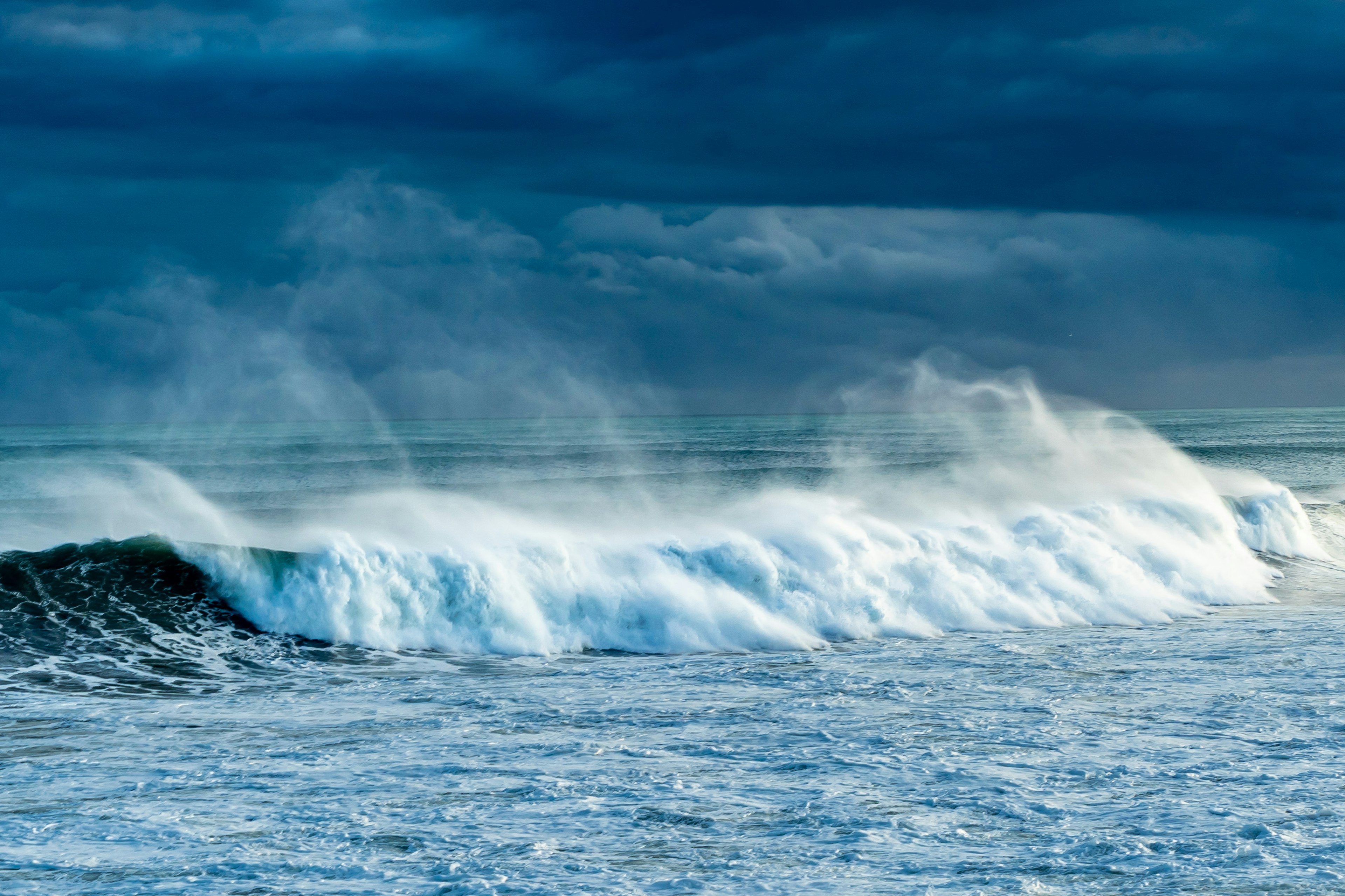 Waves crashing on a blue ocean creating white foam