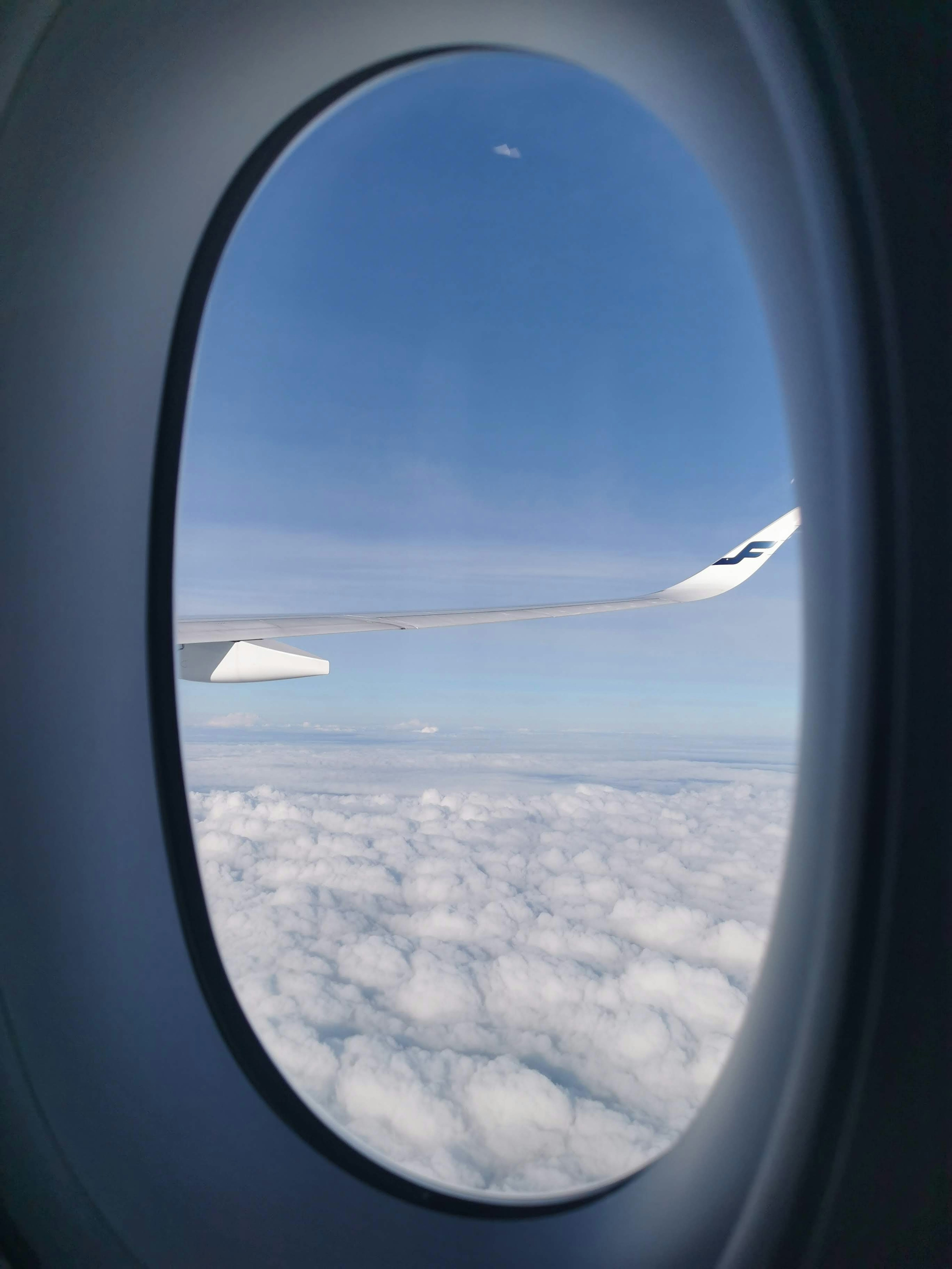 Blick auf Wolken und blauen Himmel aus einem Flugzeugfenster