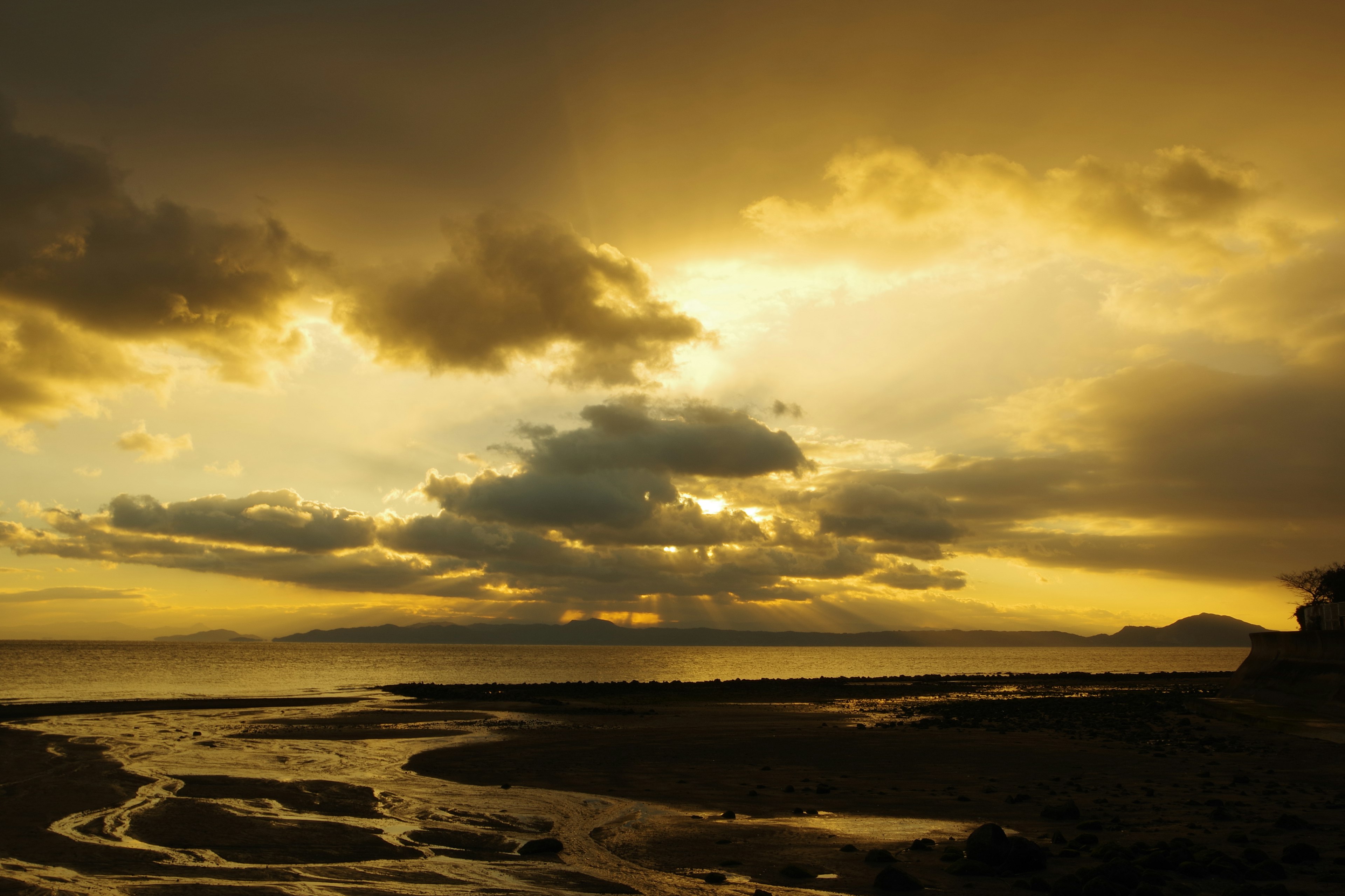 Sunset over the ocean with flowing river and dark clouds