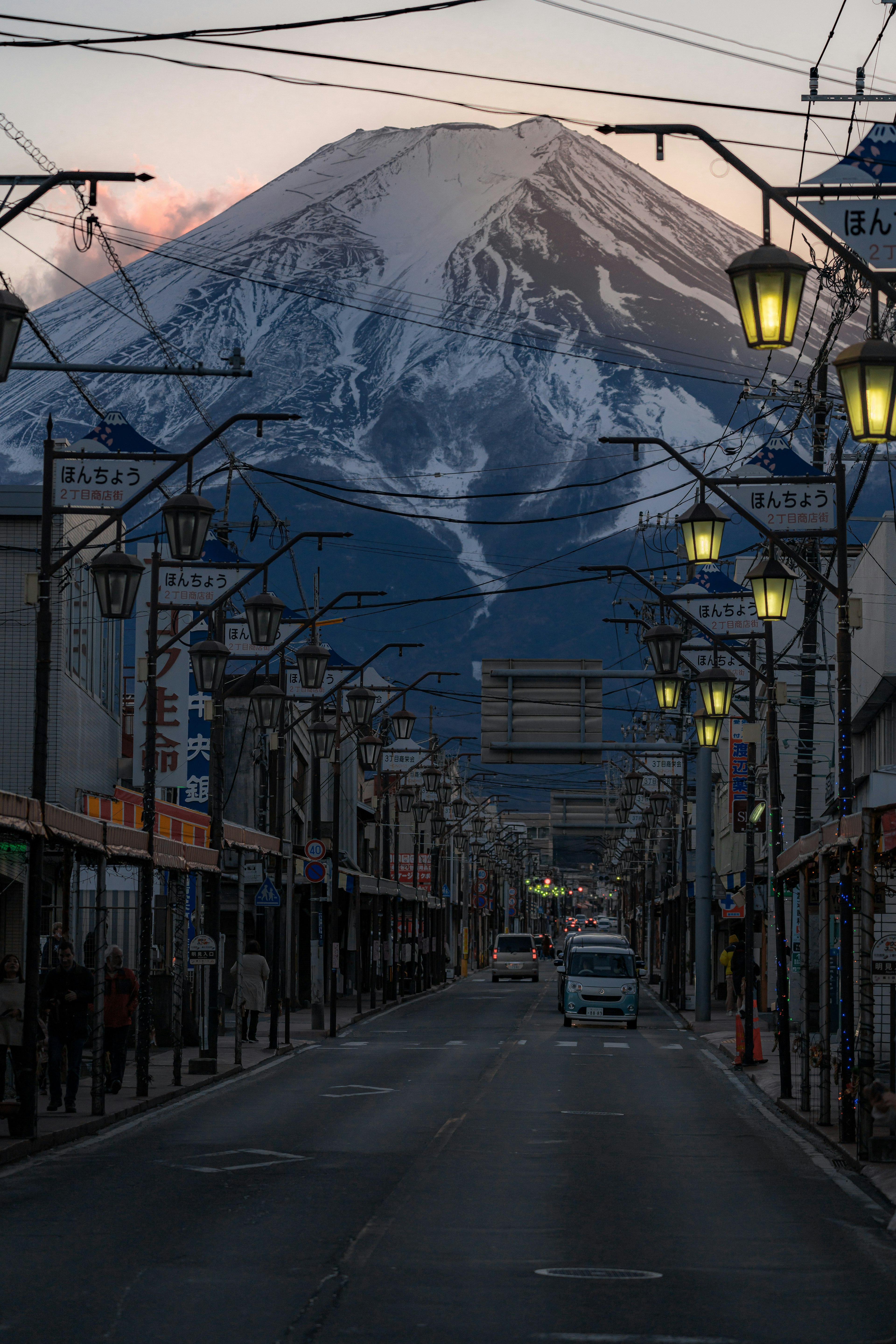 雪をかぶった富士山が背景にある静かな通りの景色