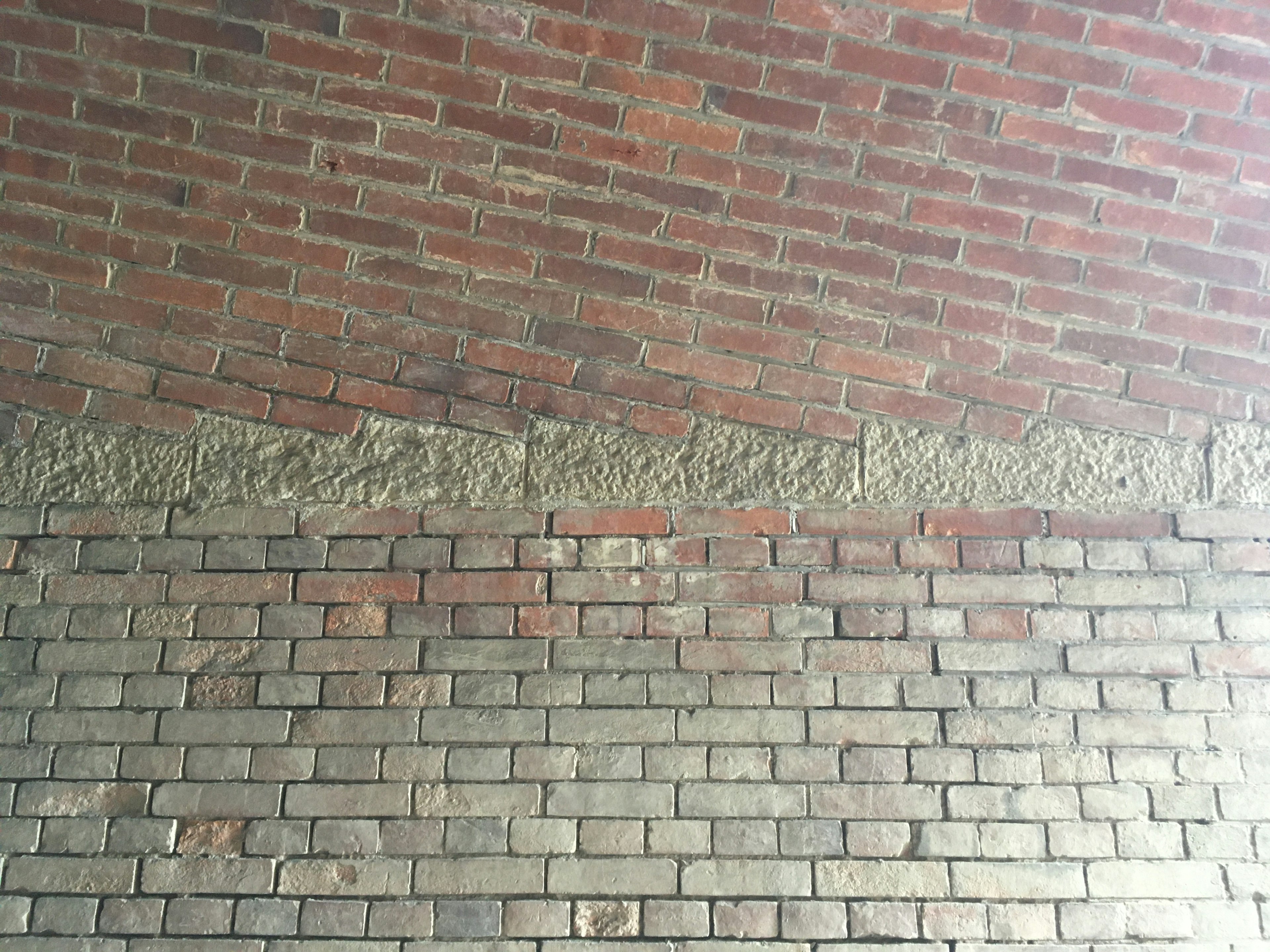 Wall structure featuring alternating red bricks and gray mortar