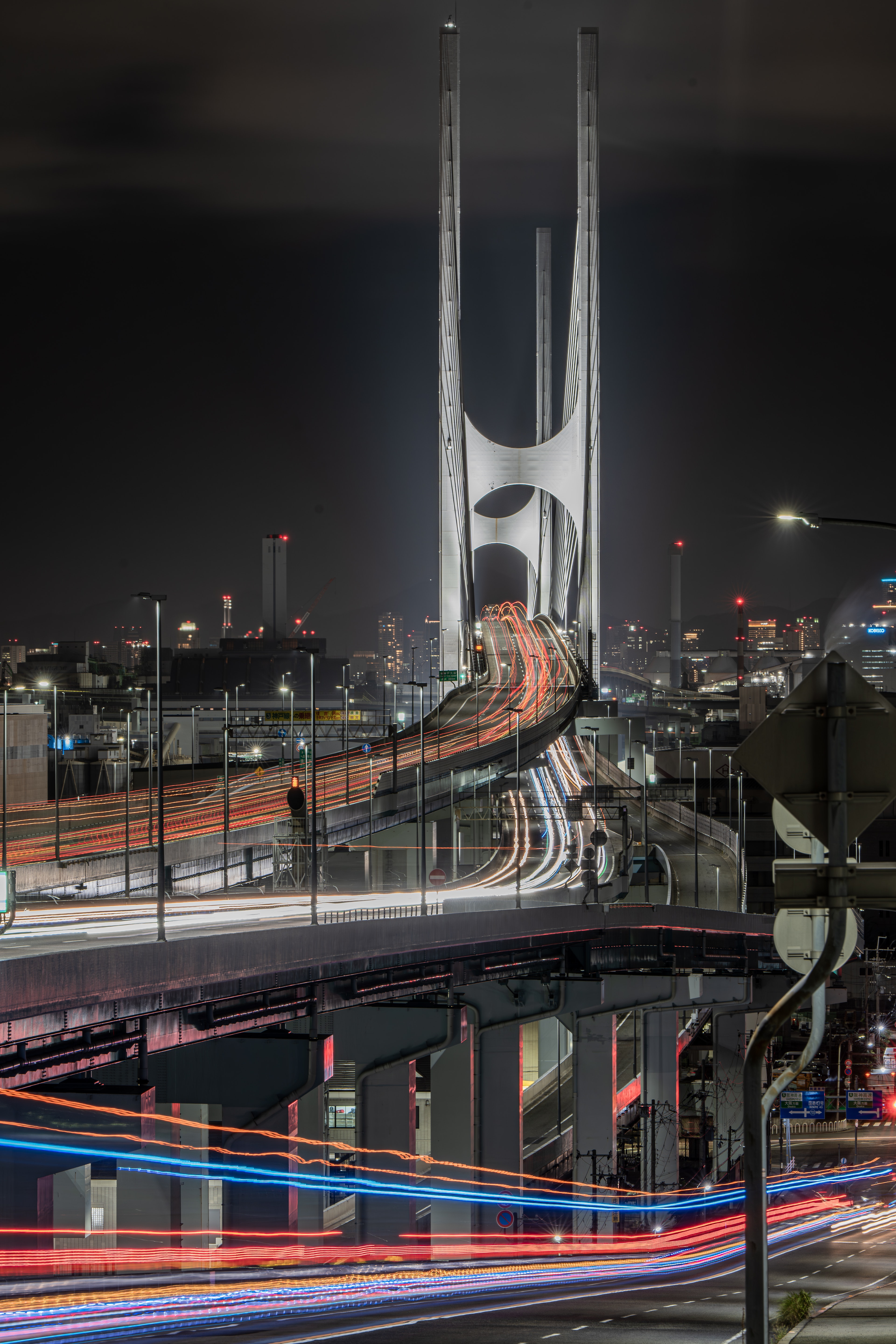 Pont au design unique s'élevant dans un paysage urbain nocturne avec des traînées de lumière des véhicules