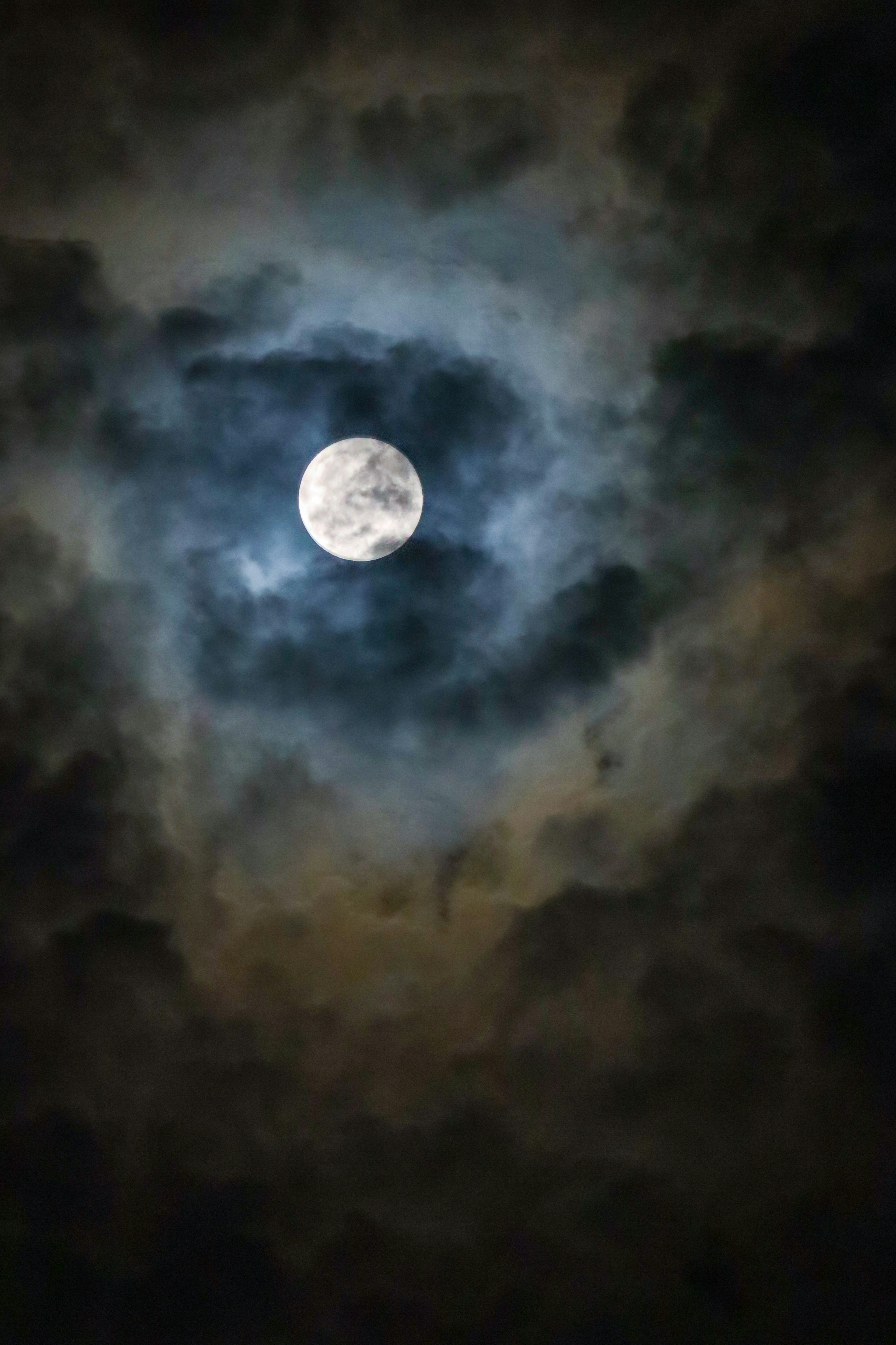 A mystical night sky featuring a glowing moon surrounded by clouds