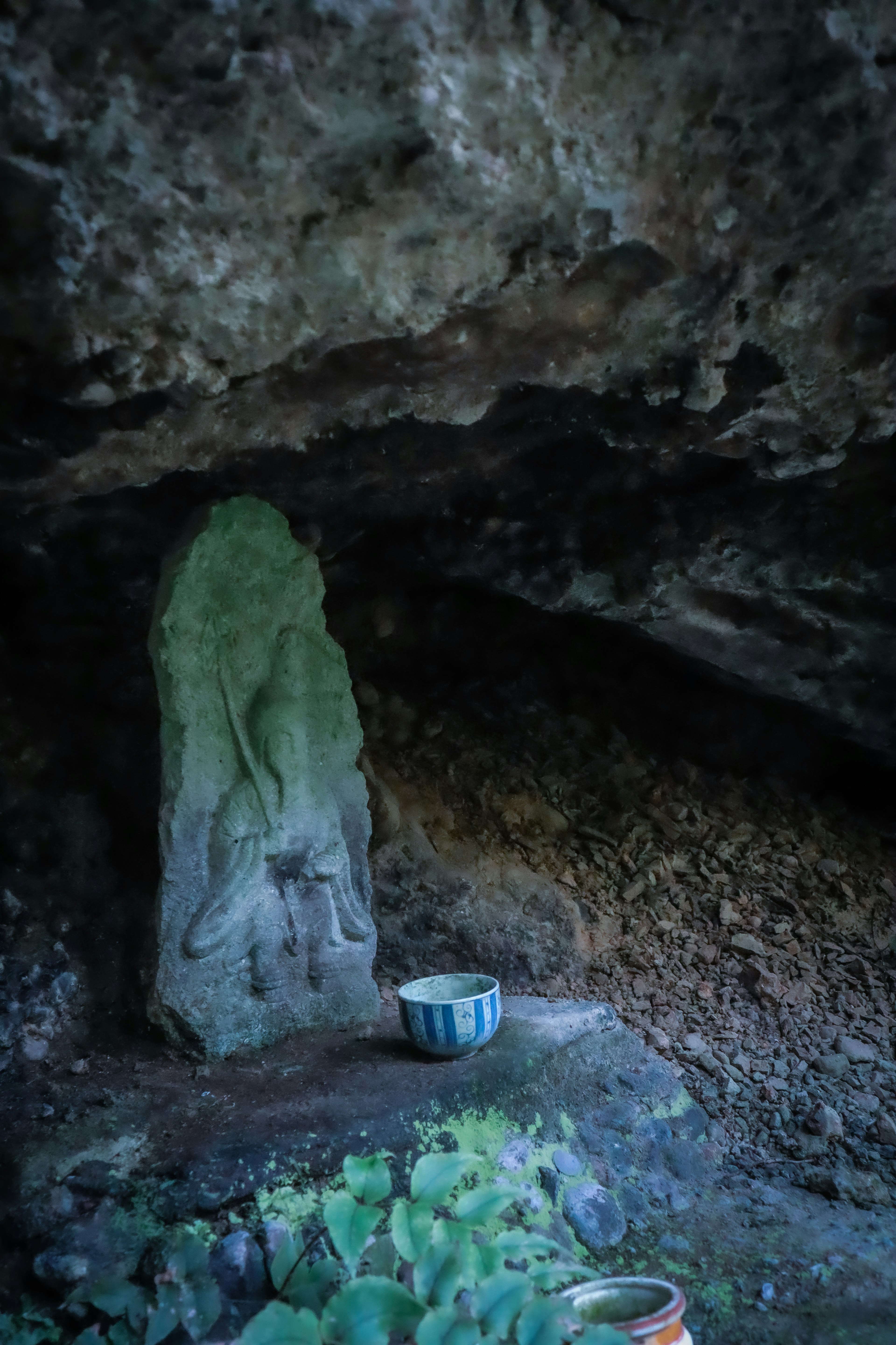 Escultura de piedra y tazón de cerámica dentro de una cueva