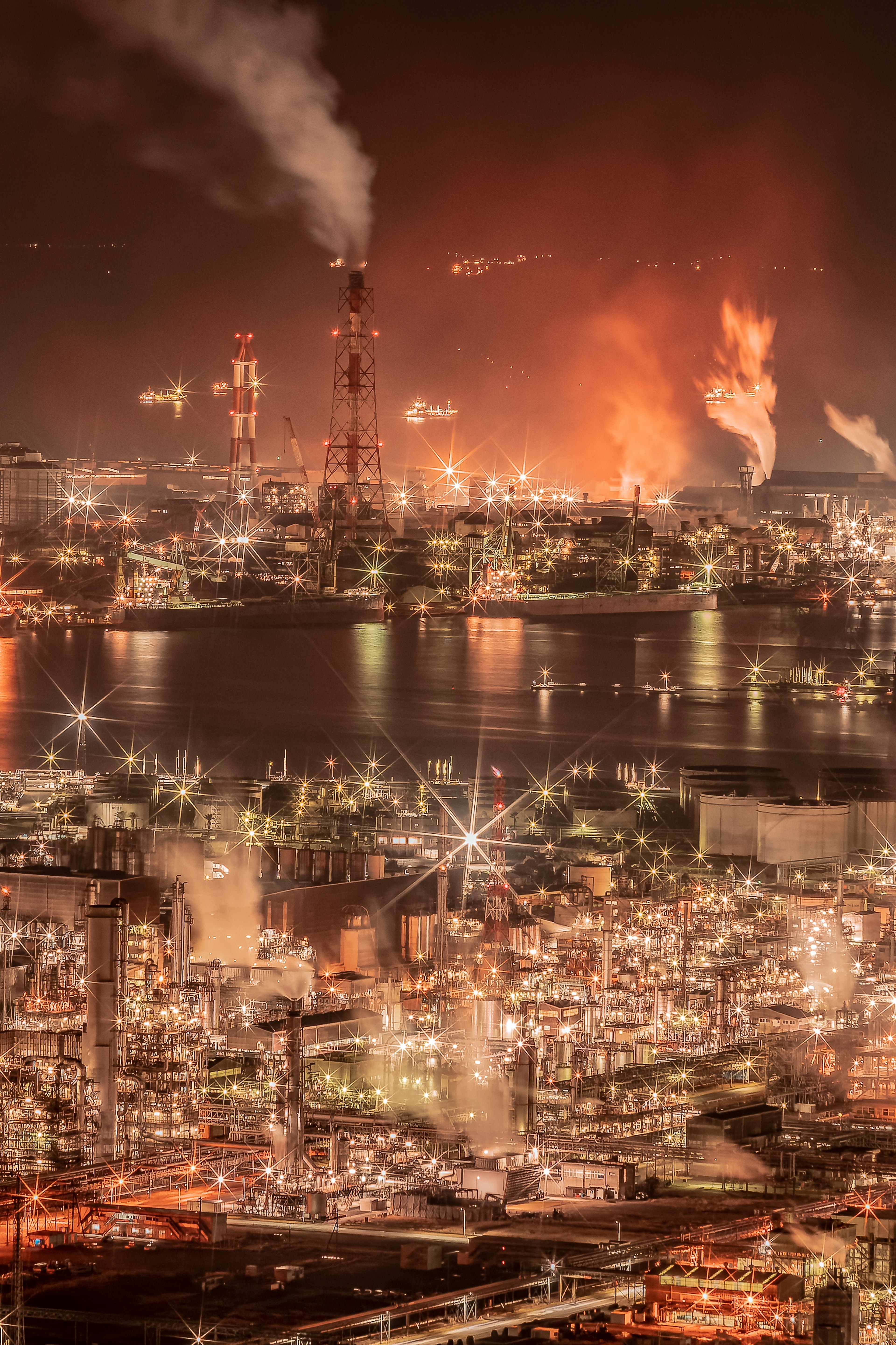 Industriegebiet bei Nacht mit rauchenden Schornsteinen und Flammen