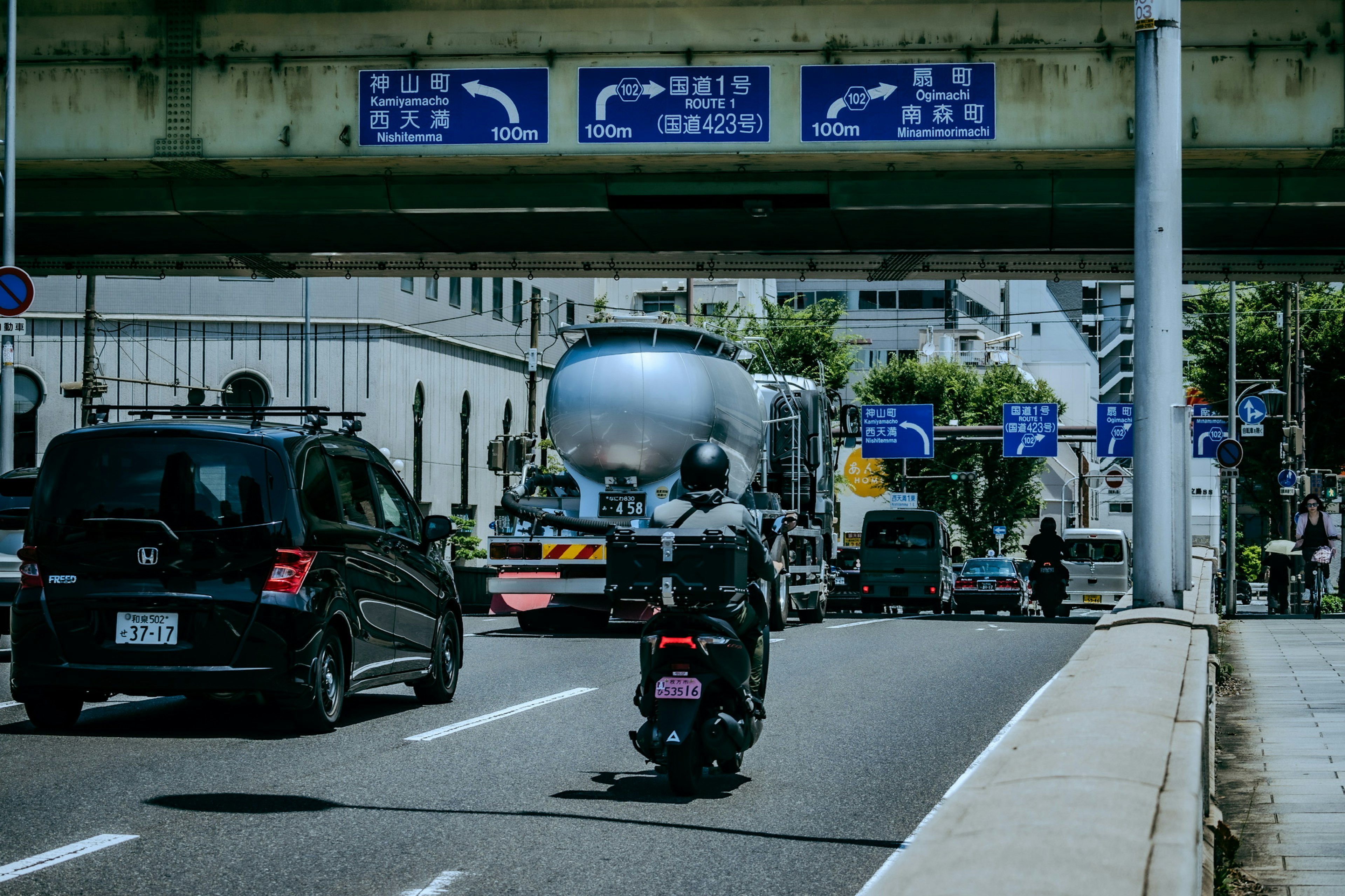 摩托车和车辆在交通标志下的道路上