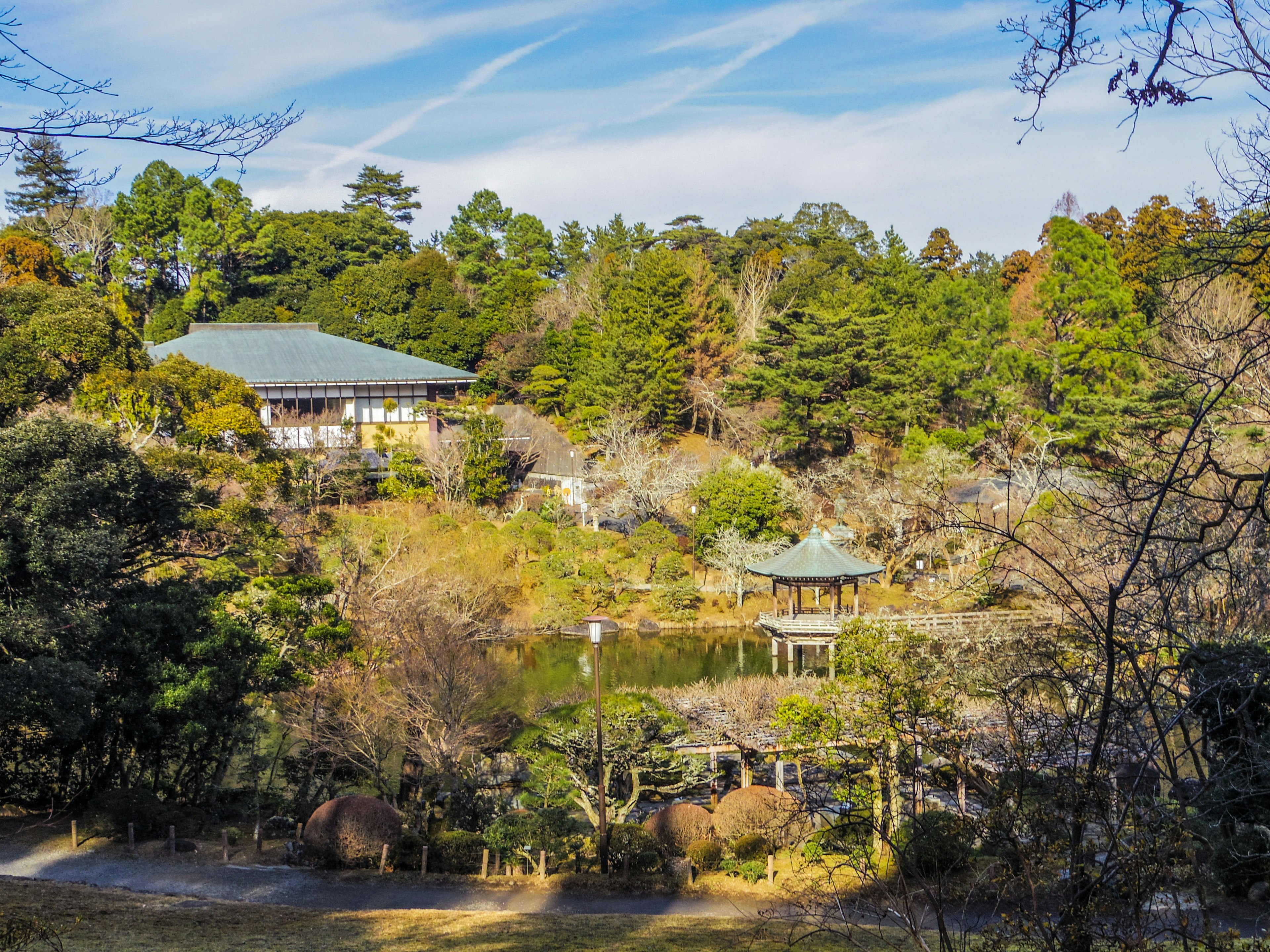 Malersicher Blick auf ein traditionelles japanisches Gebäude und einen Teich in einem üppigen Park