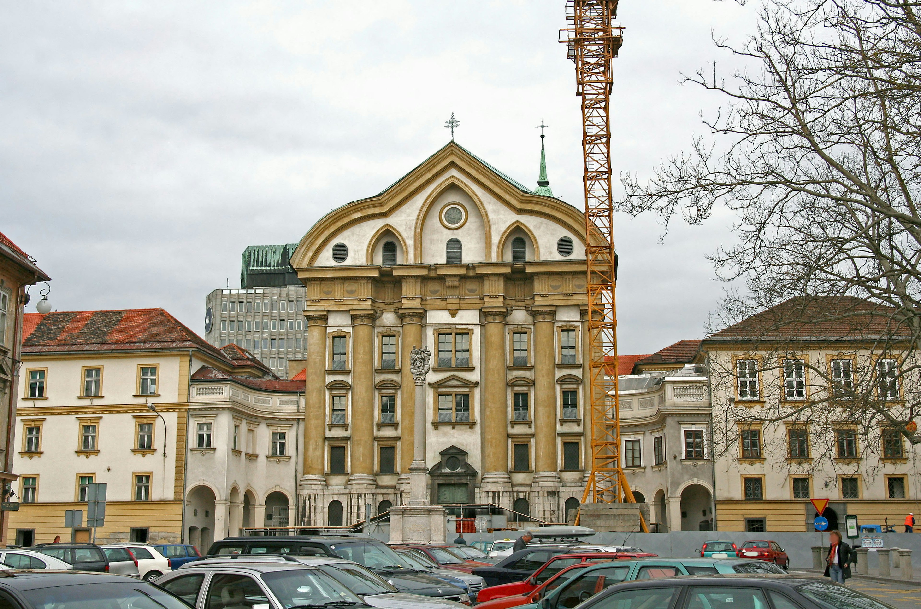 Historisches Gebäude mit Parkplatz davor und einem Kran im Hintergrund