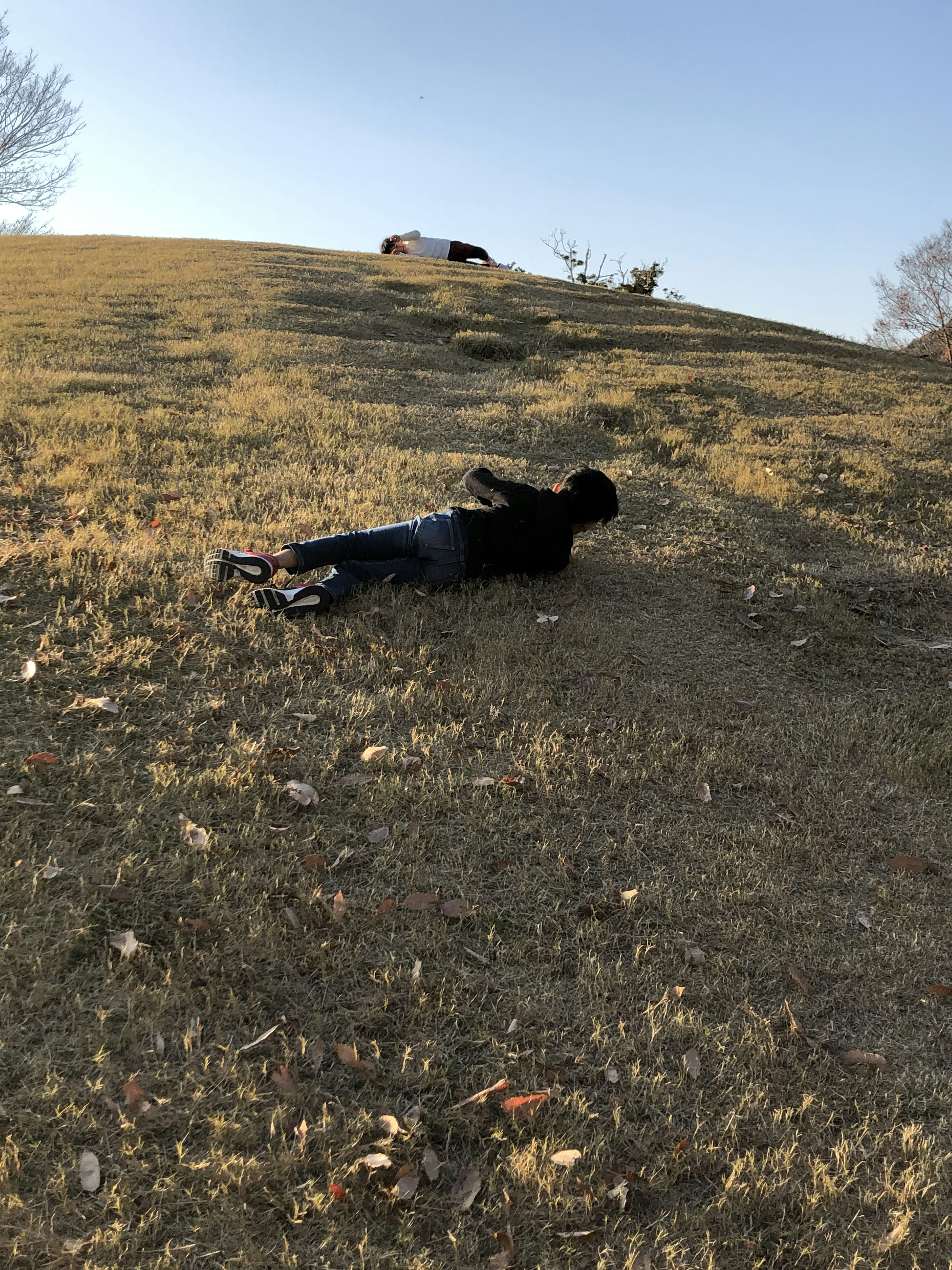 草地で寝そべる人と背景の丘