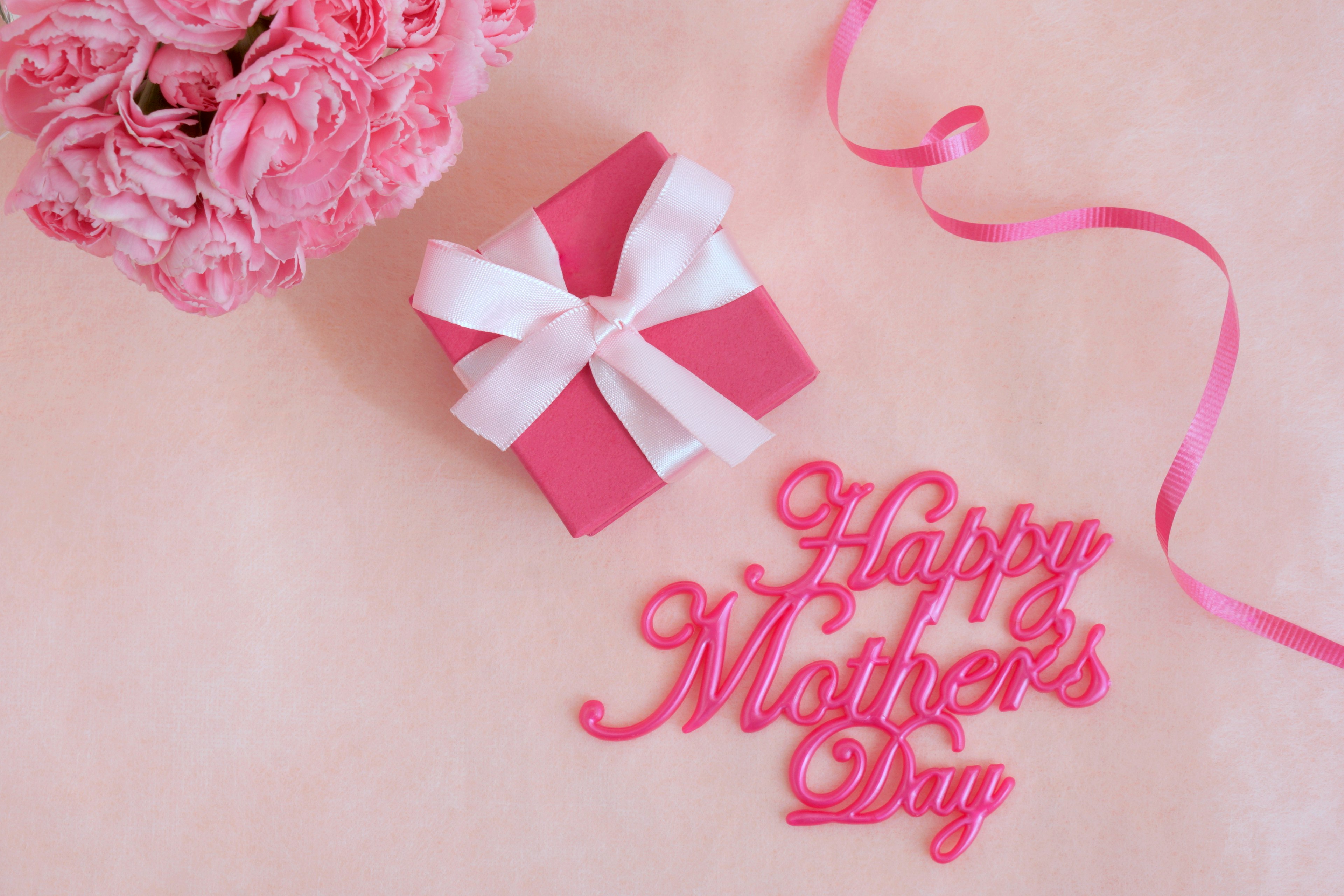 A pink background with a bouquet and a gift celebrating Mother's Day