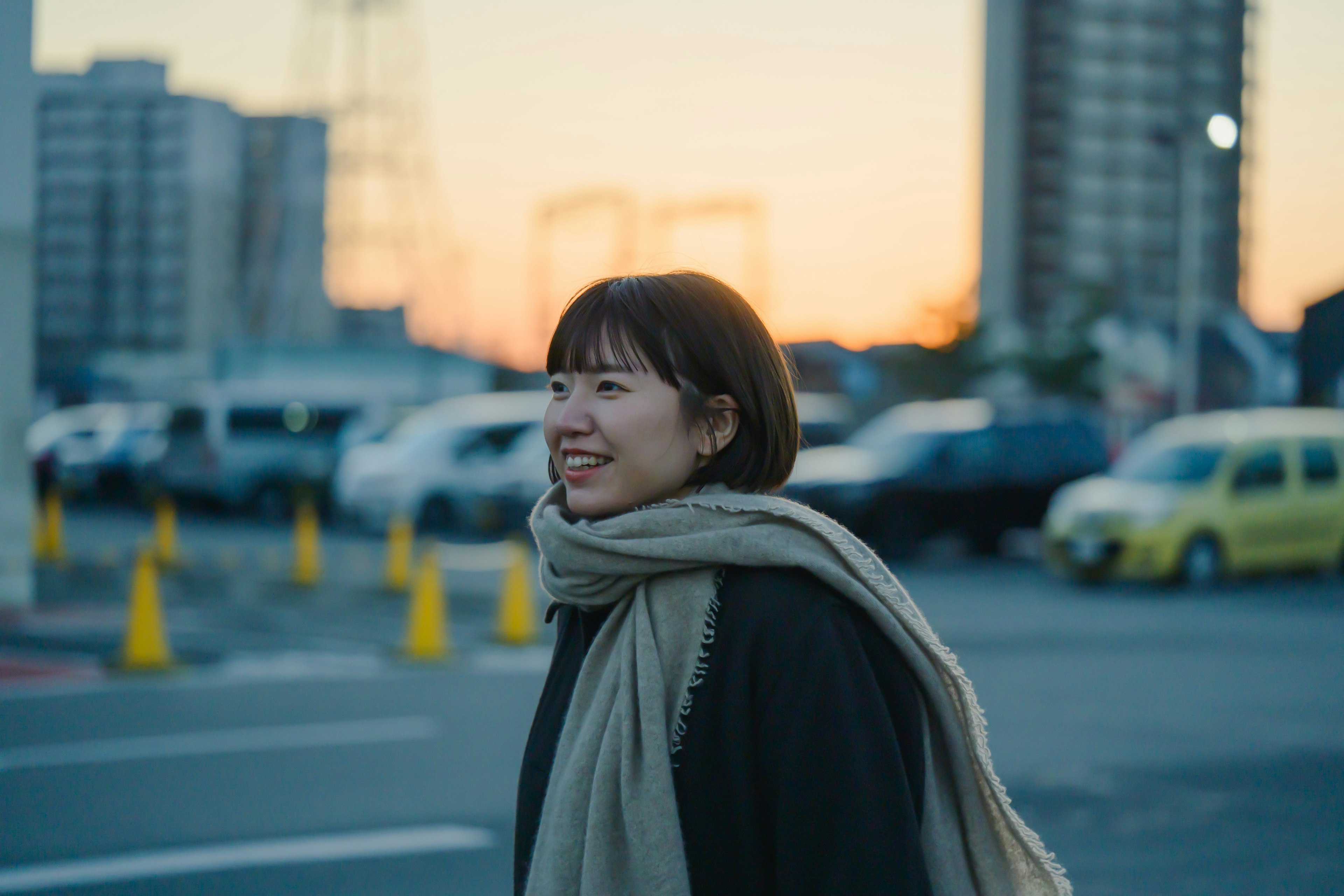 Retrato de una mujer con el atardecer de fondo paisaje urbano y coches visibles