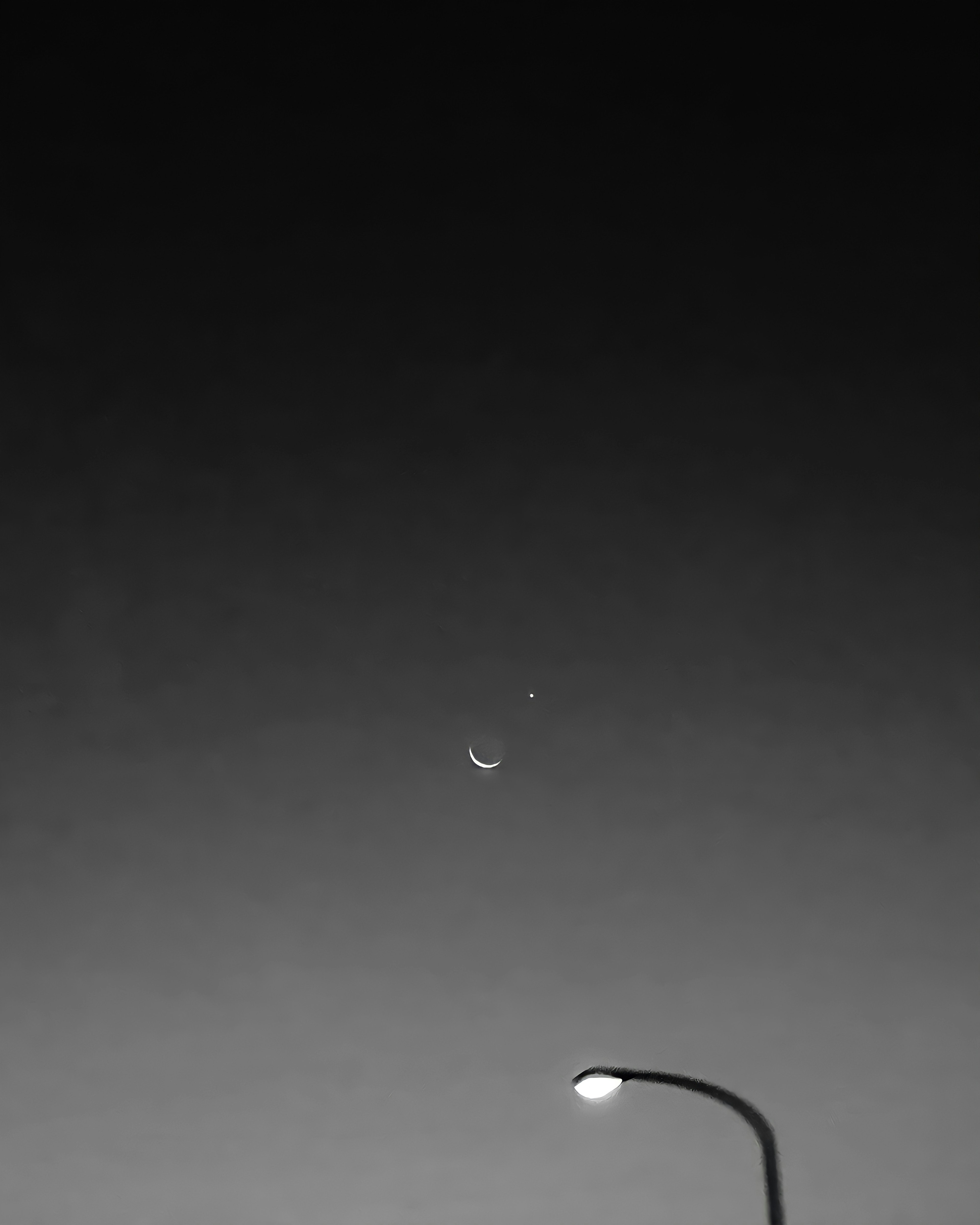 Close-up of a streetlight and a water droplet against a black and white sky