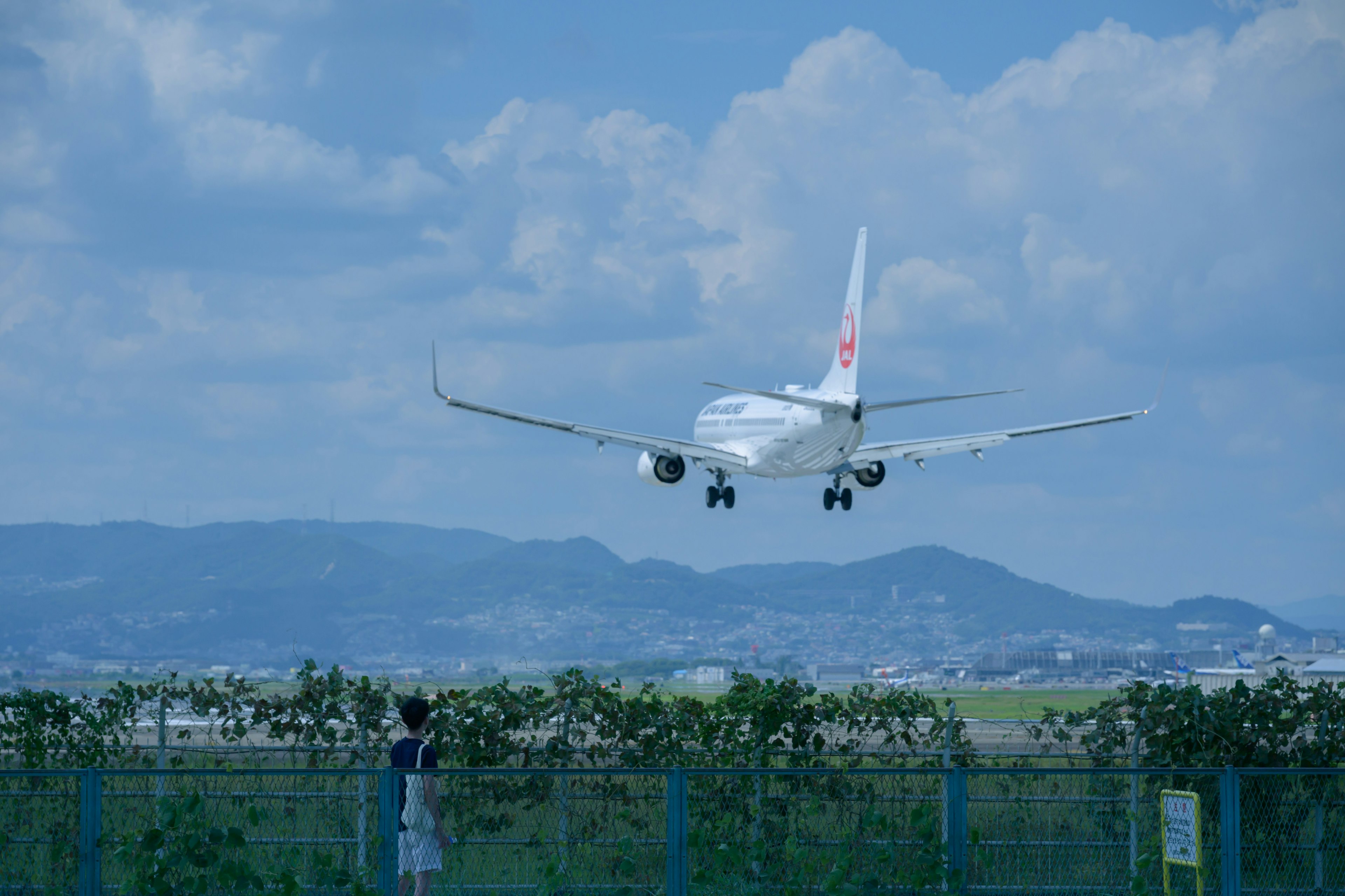 青空の下で着陸する飛行機と遠くの山々