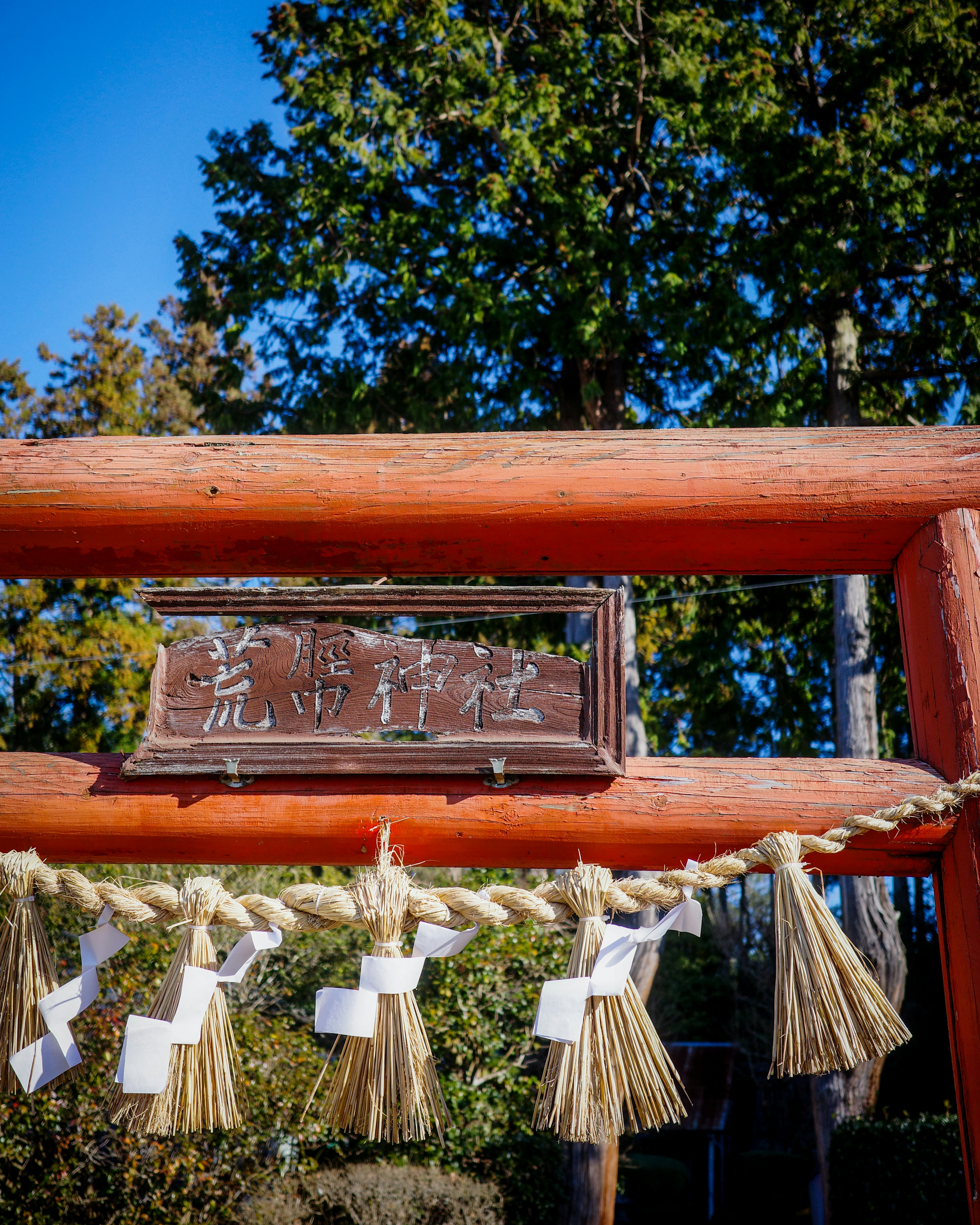 赤い鳥居と木製の看板がある神社の入口