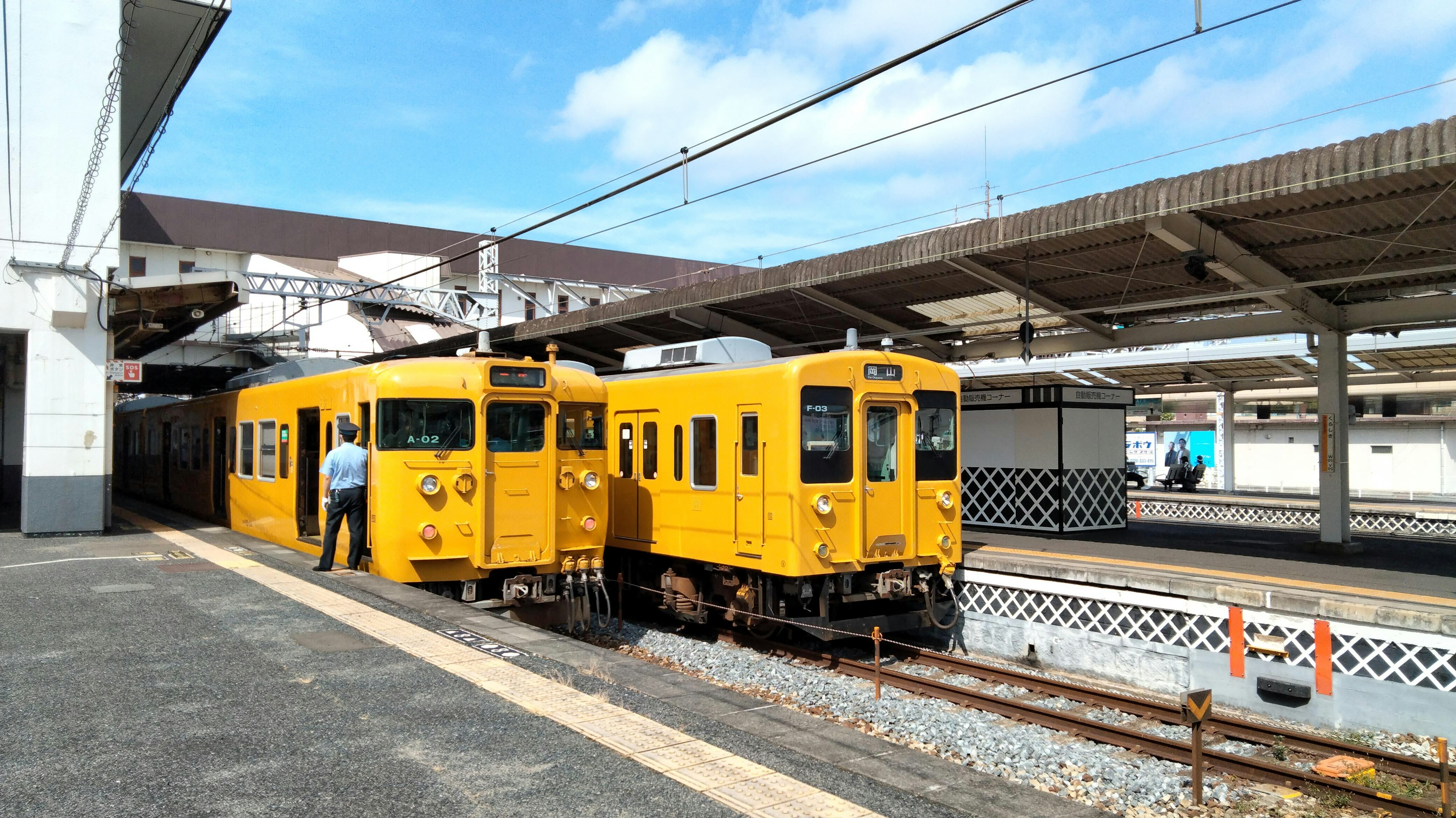 Yellow trains at a station under a blue sky