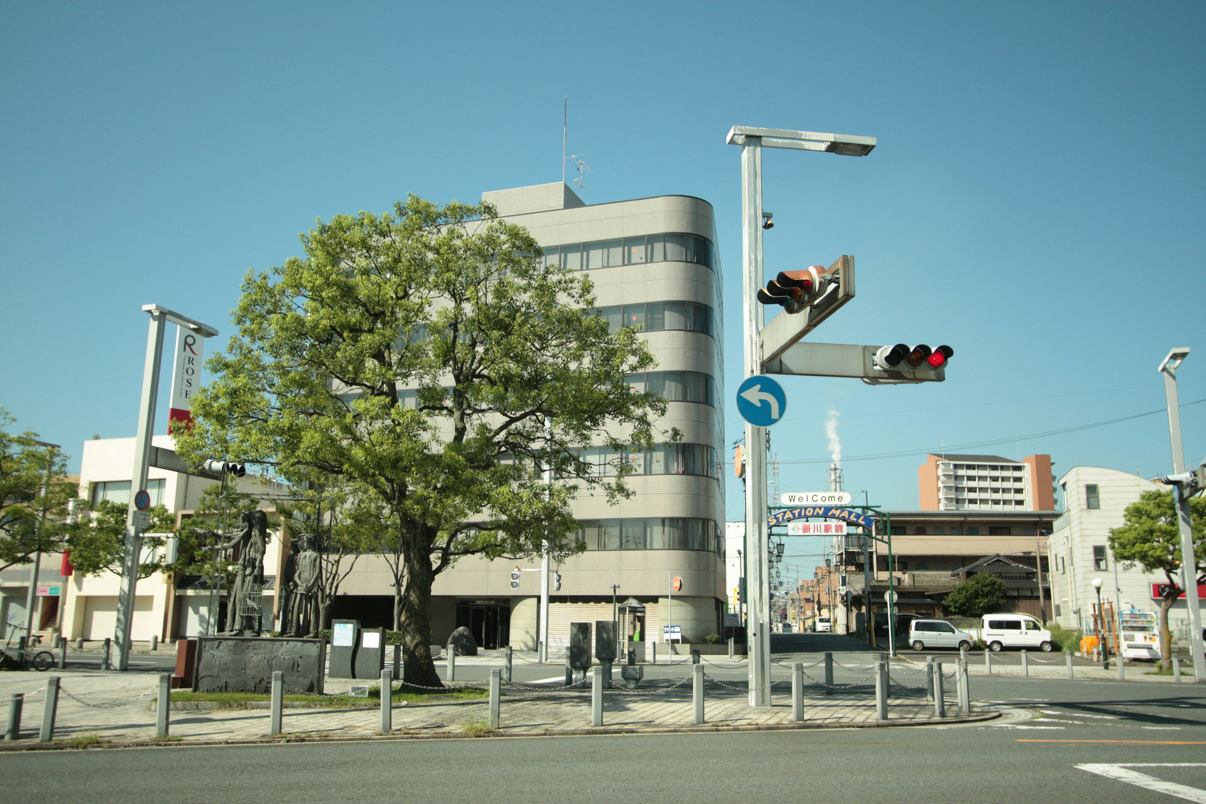 Bâtiment moderne à un carrefour avec des feux de circulation sous un ciel bleu clair