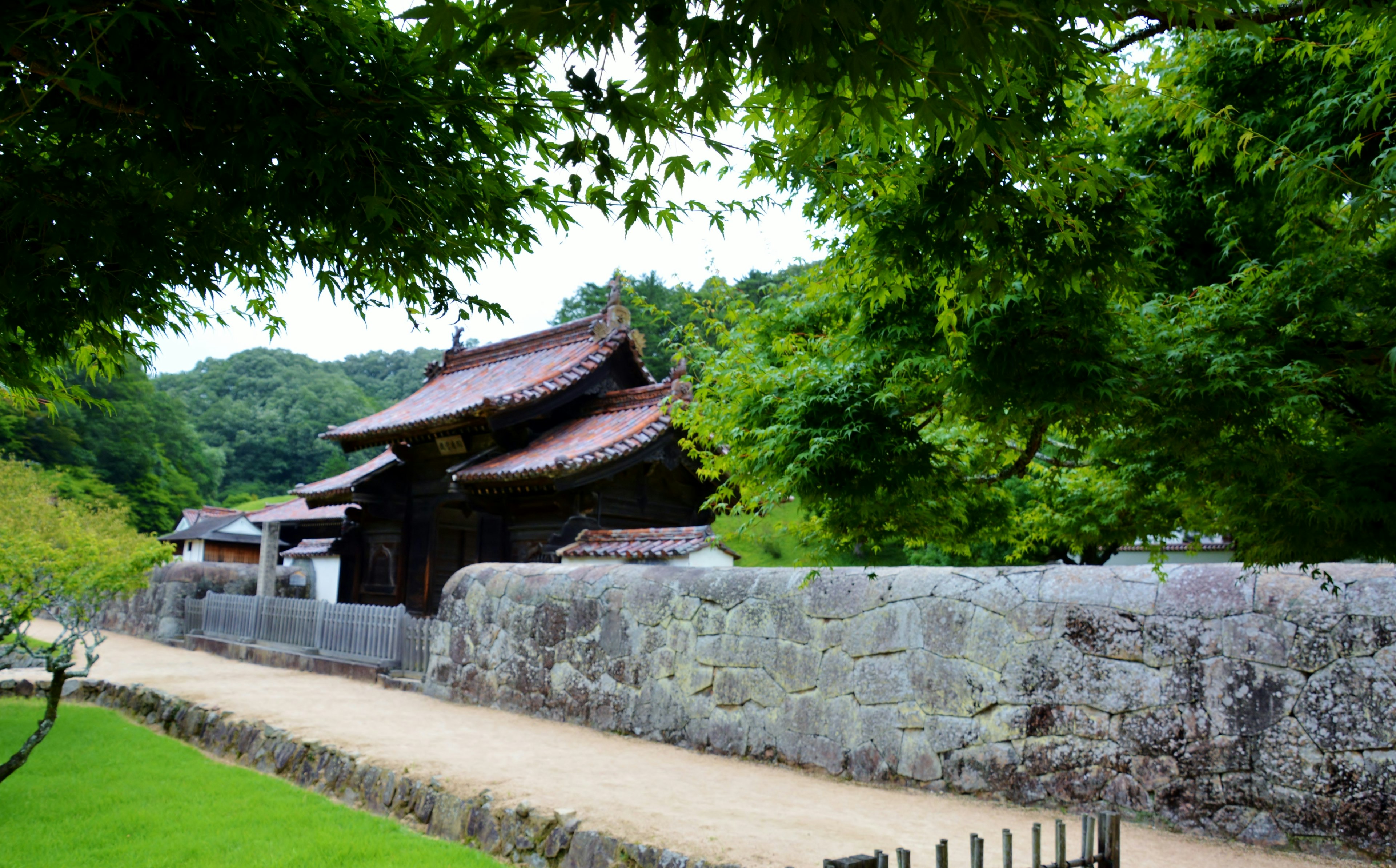 古老寺庙的风景，周围围绕着石墙和郁郁葱葱的绿树