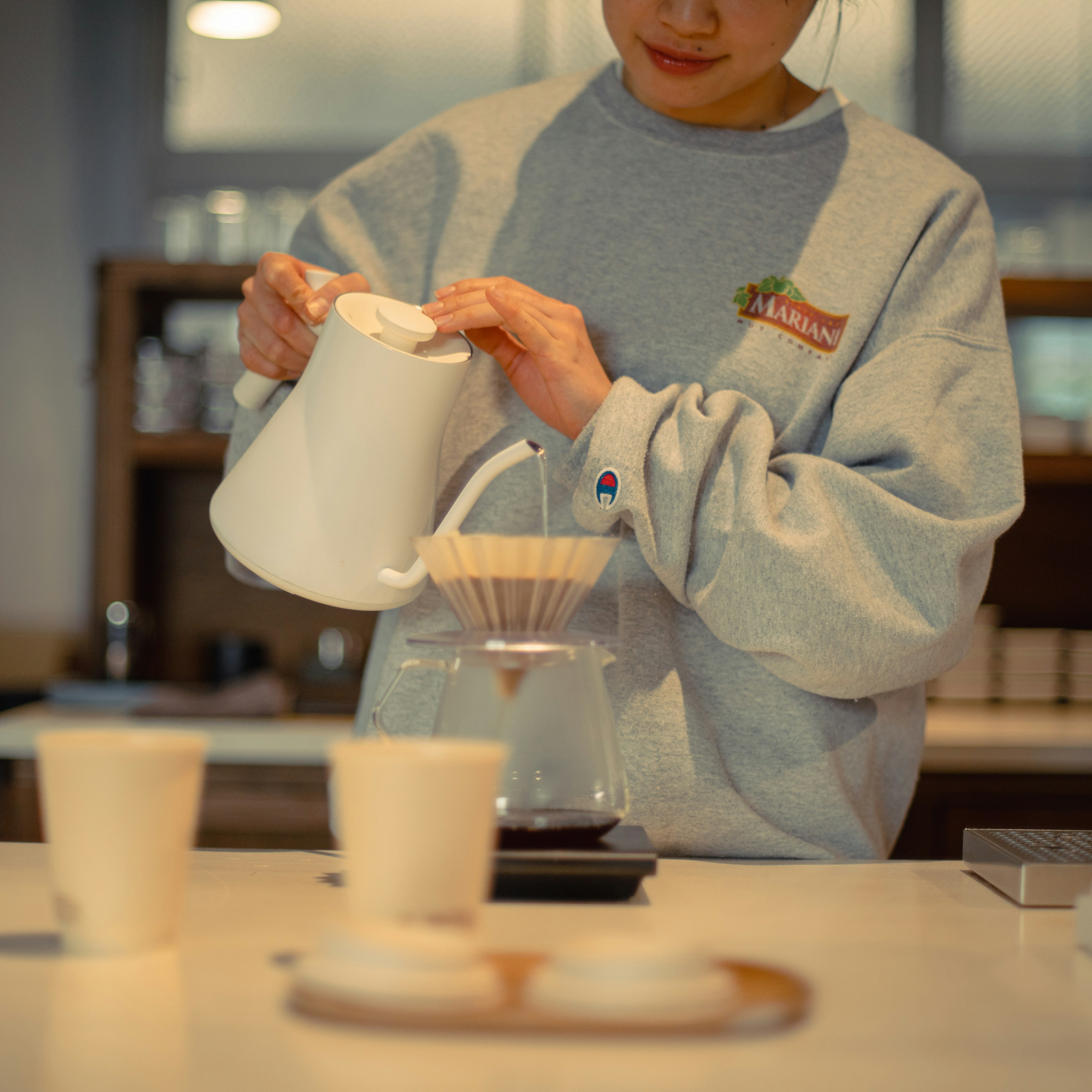 Una mujer vertiendo café con una tetera sobre un filtro