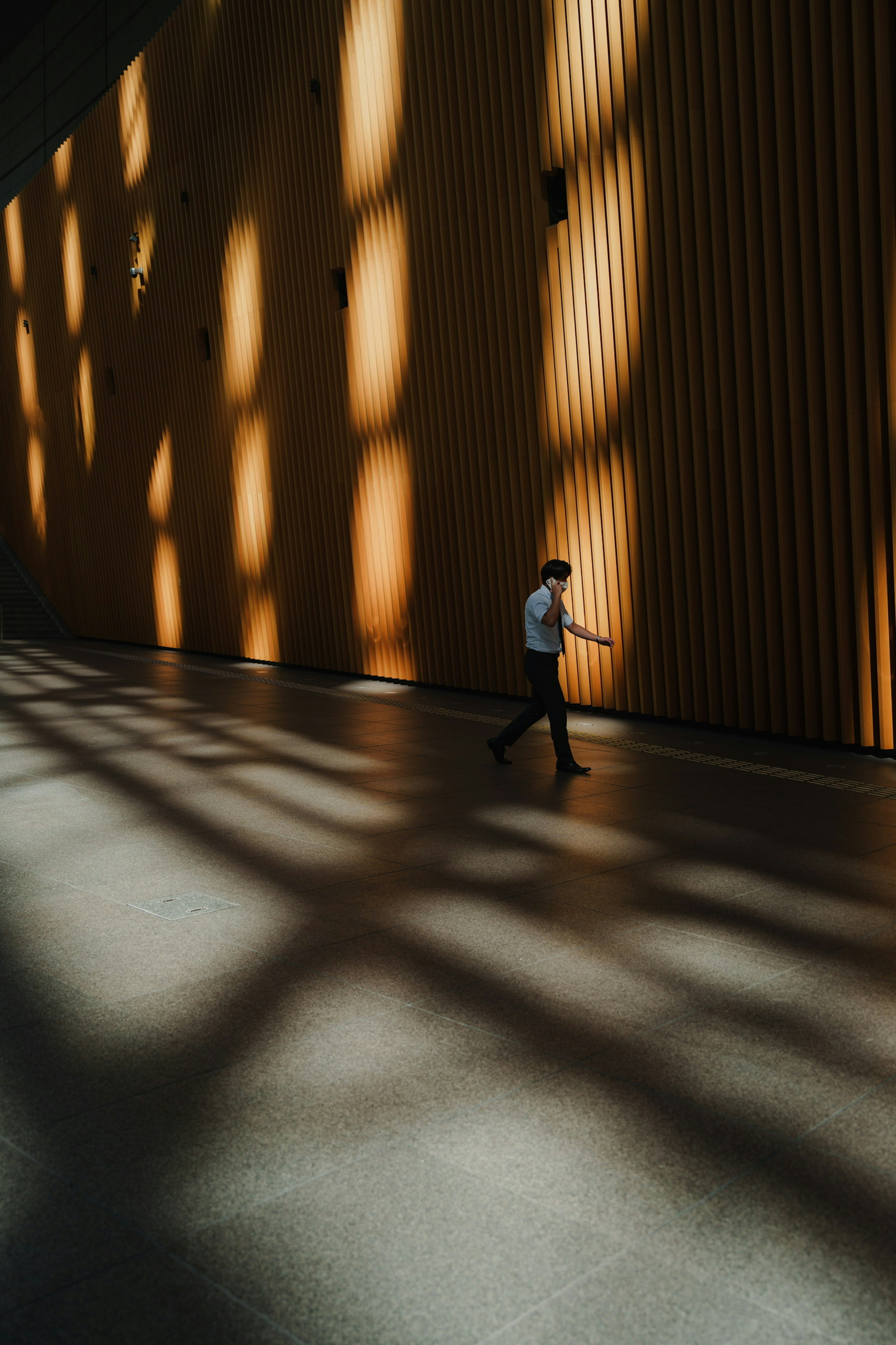 Silhouette eines Mannes, der vor einer schattierten Wand geht