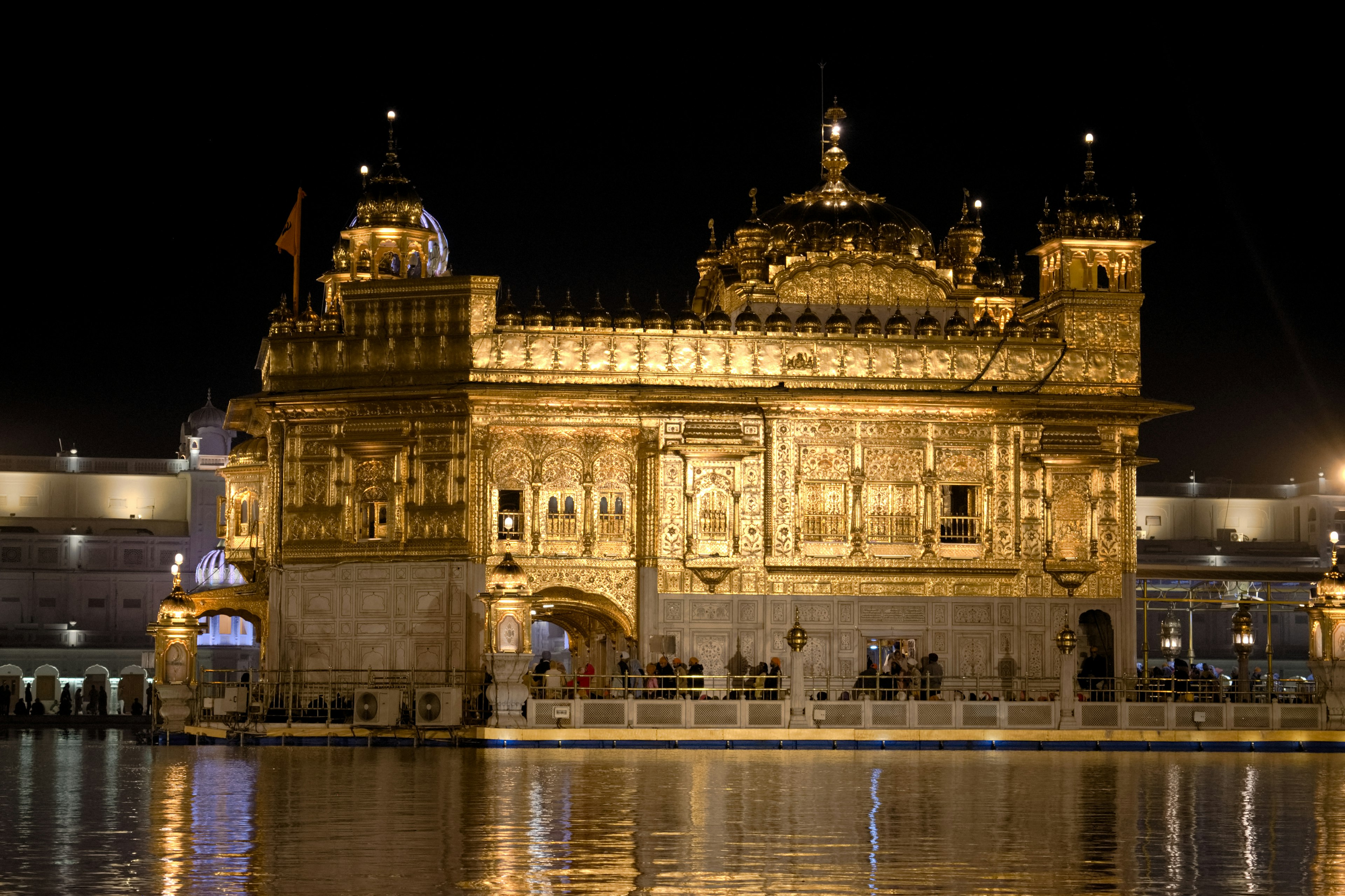 Goldener Tempel bei Nacht beleuchtet mit Reflexionen im Wasser