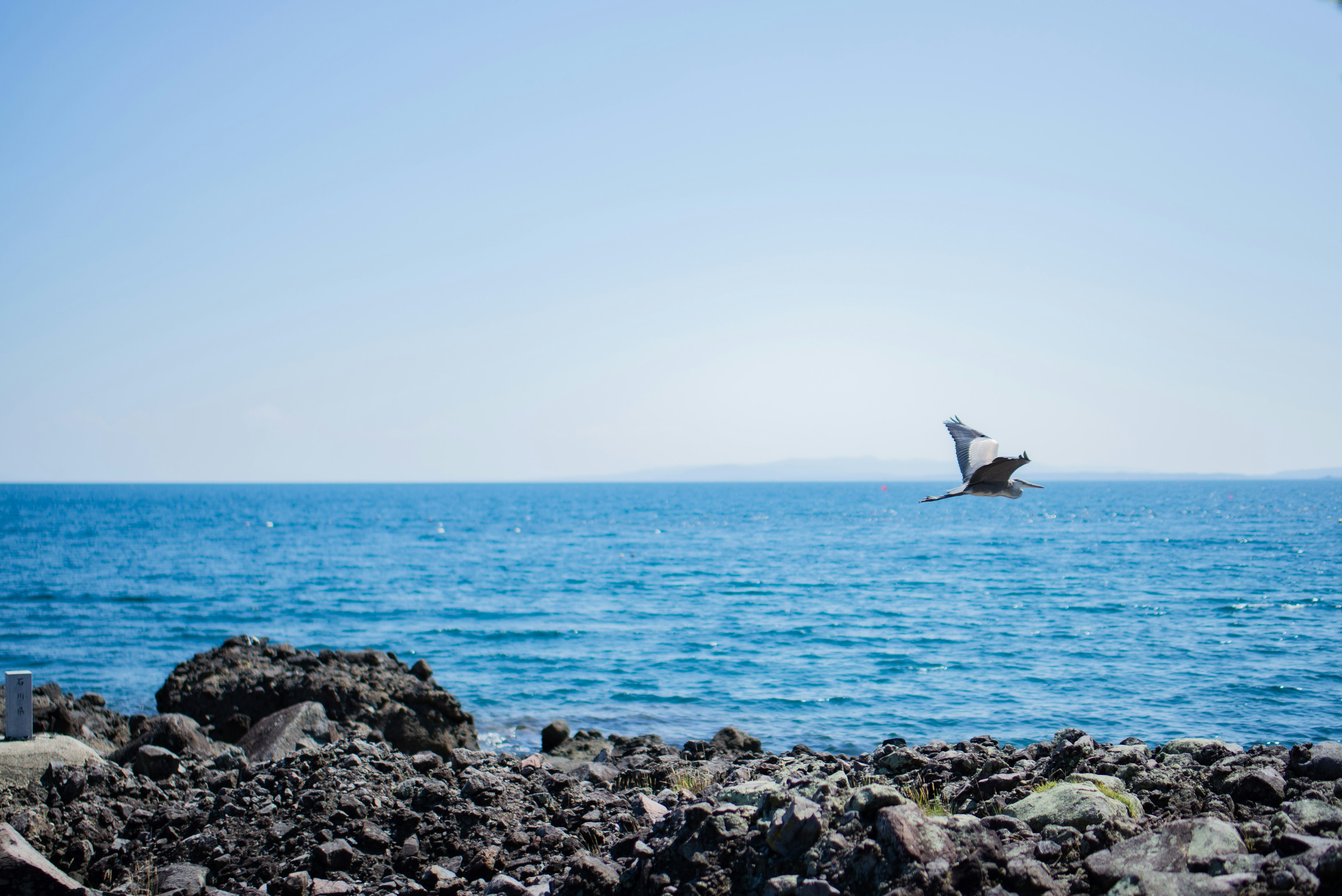 Una piccola barca che galleggia su un mare blu con una costa rocciosa