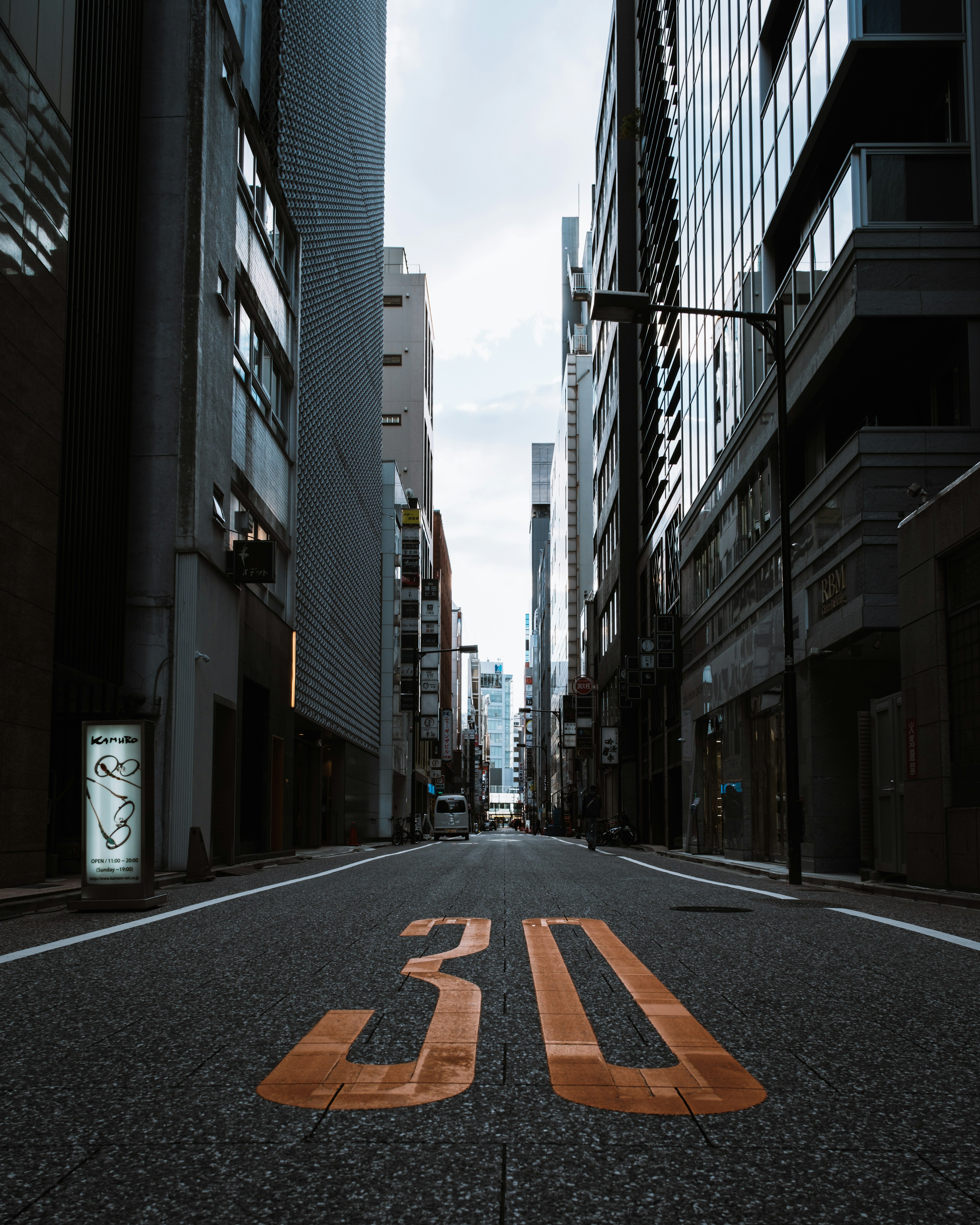 Quiet city street featuring the number 30 painted on the asphalt and skyscrapers