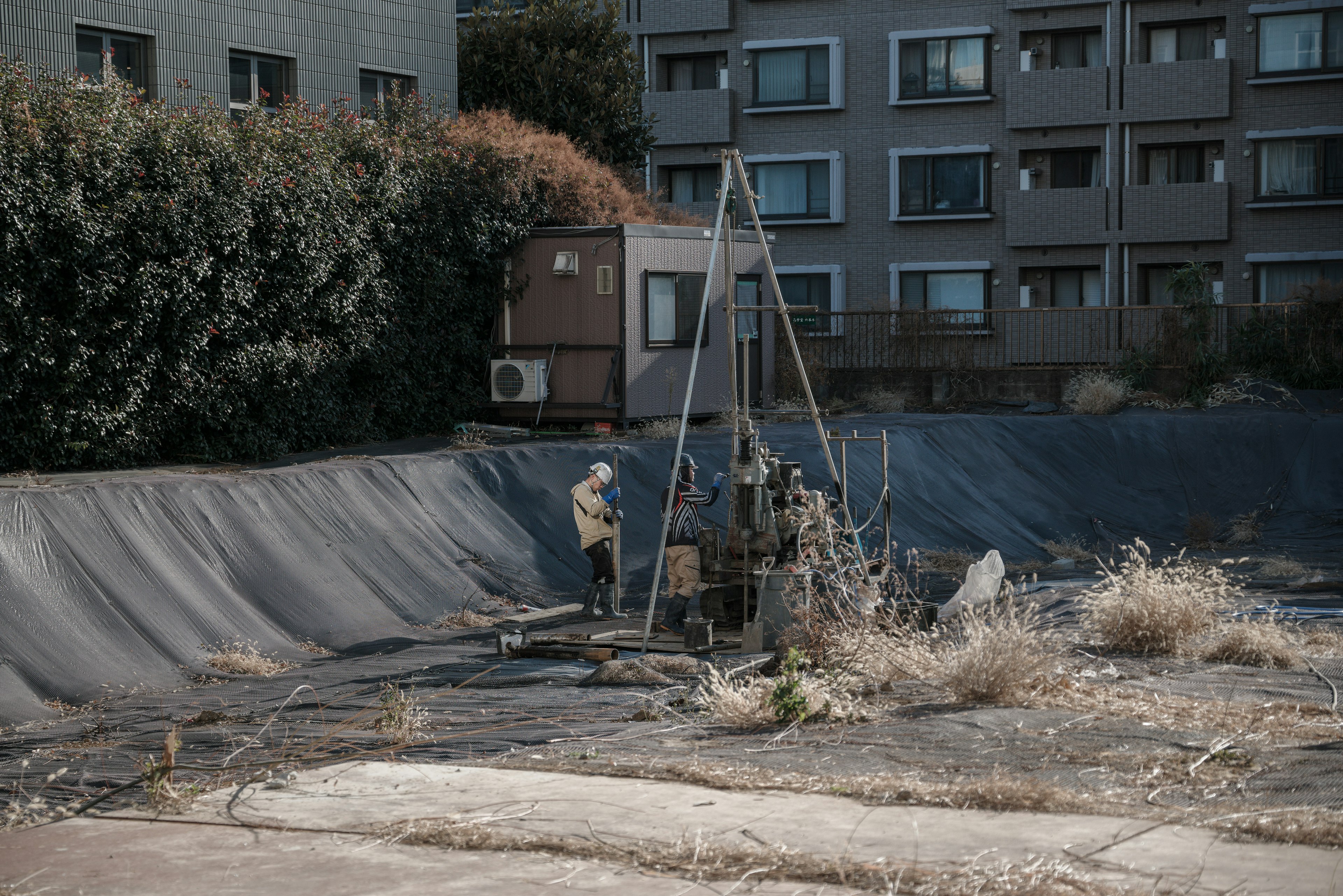 空き地で作業する人々と周囲の建物