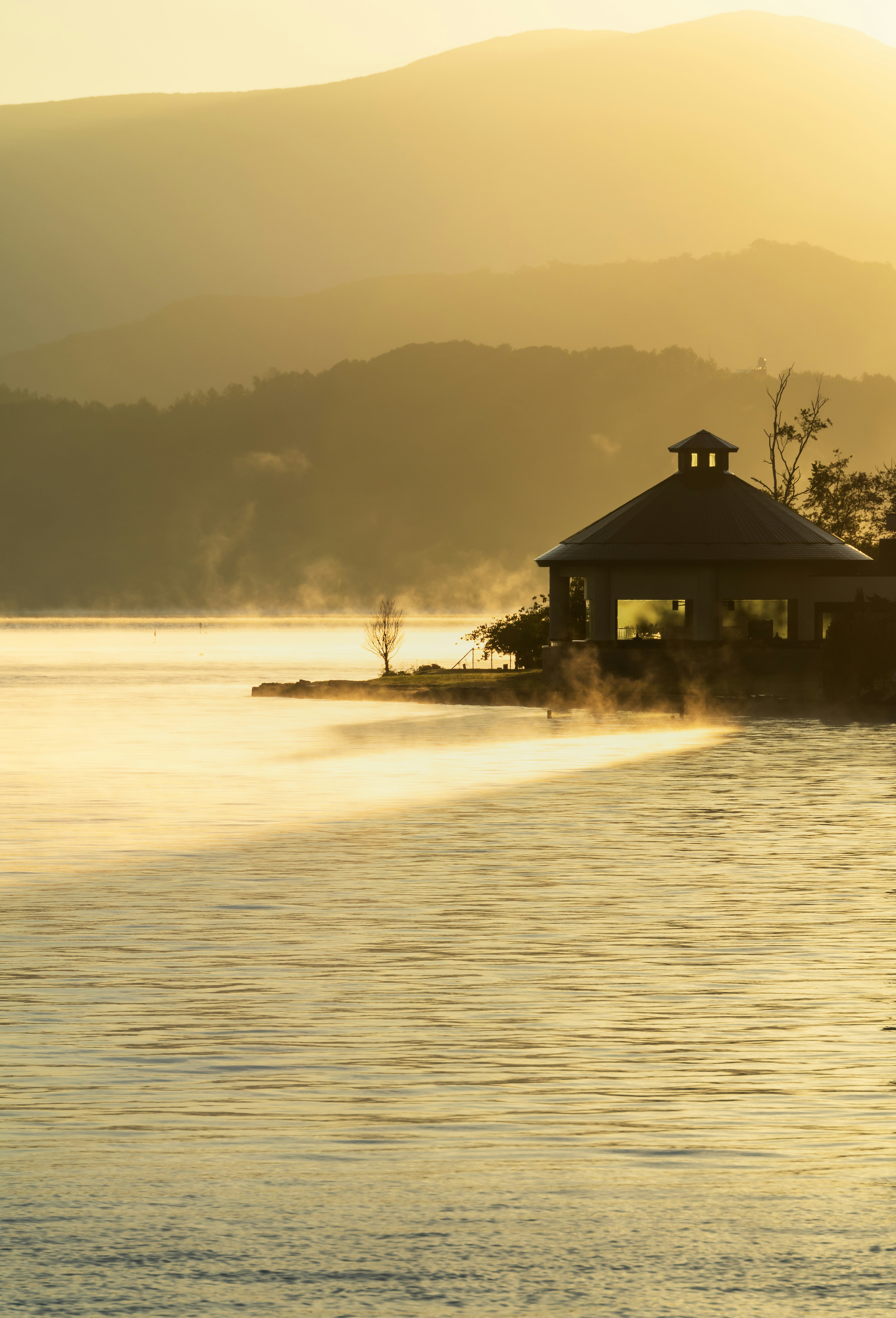 Gazebo di tepi danau dikelilingi kabut pagi