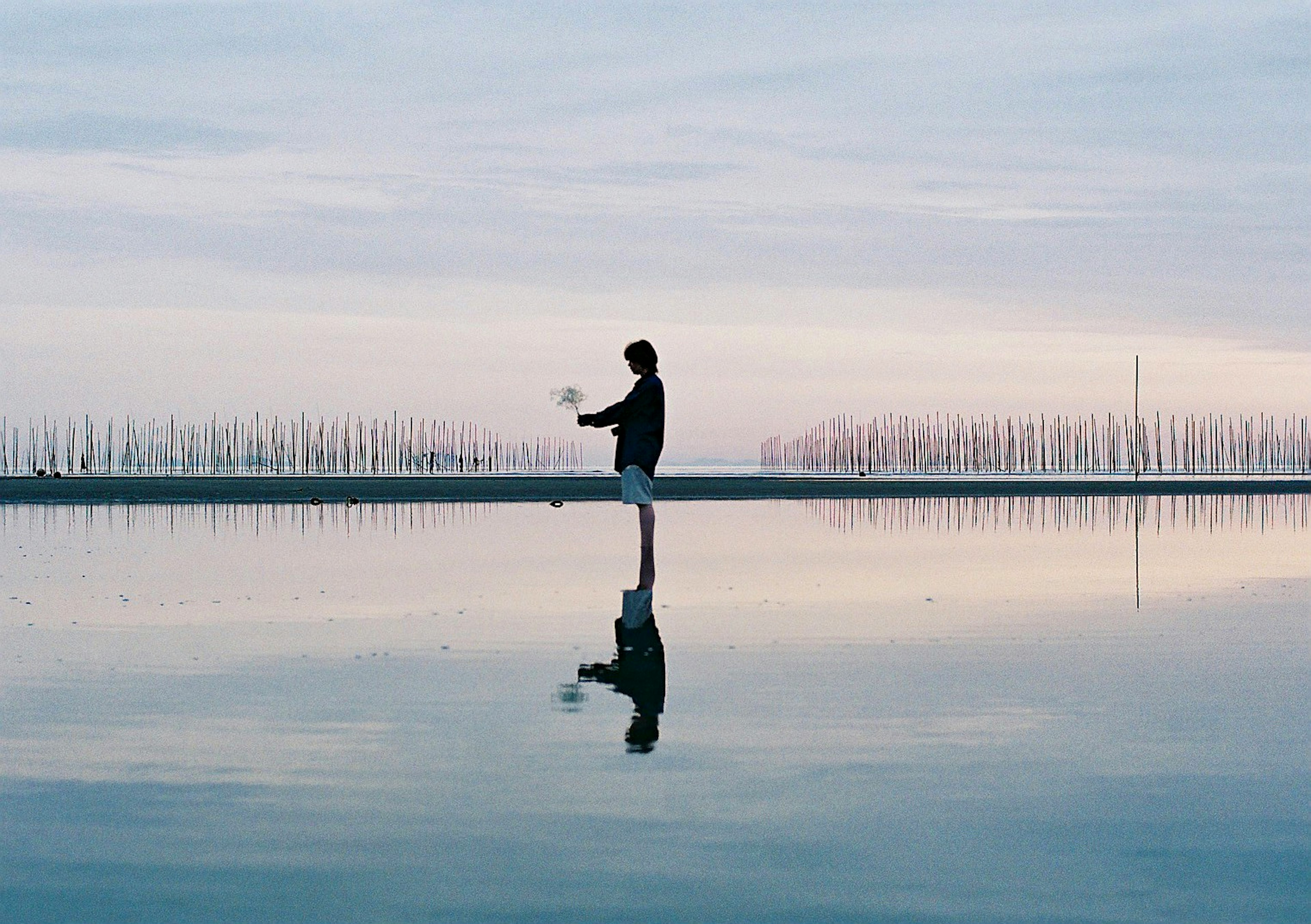 Person standing on a calm water surface with reflection