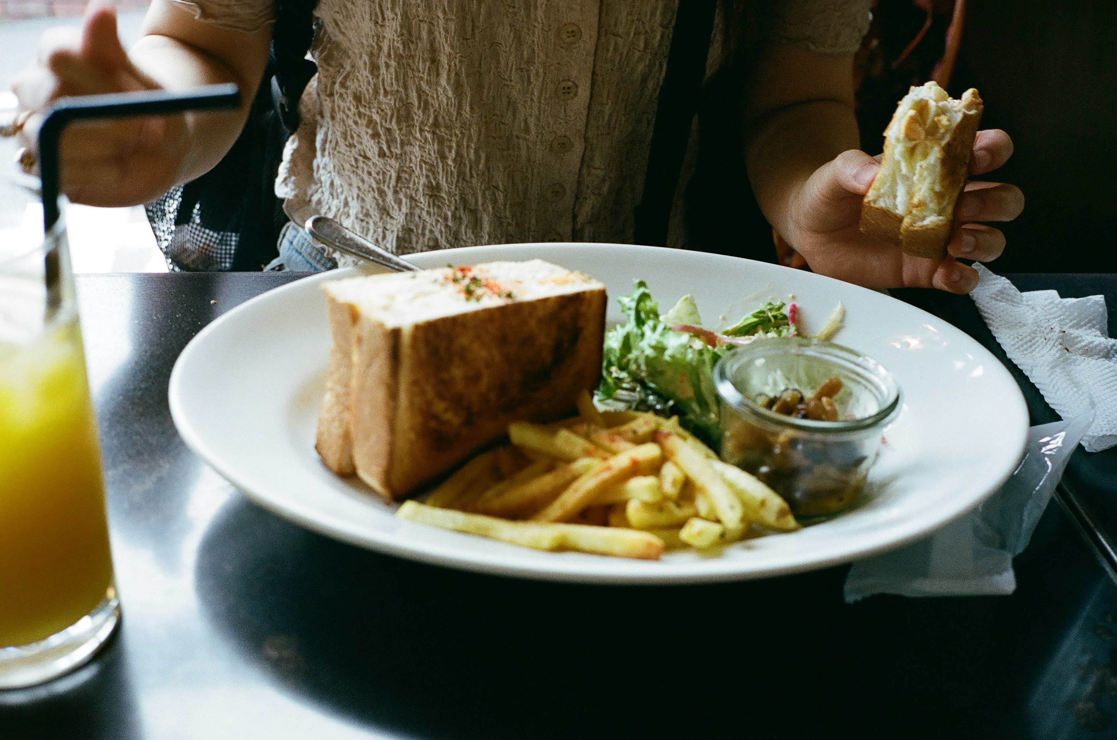 Ein Teller mit Essen auf einem Tisch mit einem Sandwich und Pommes