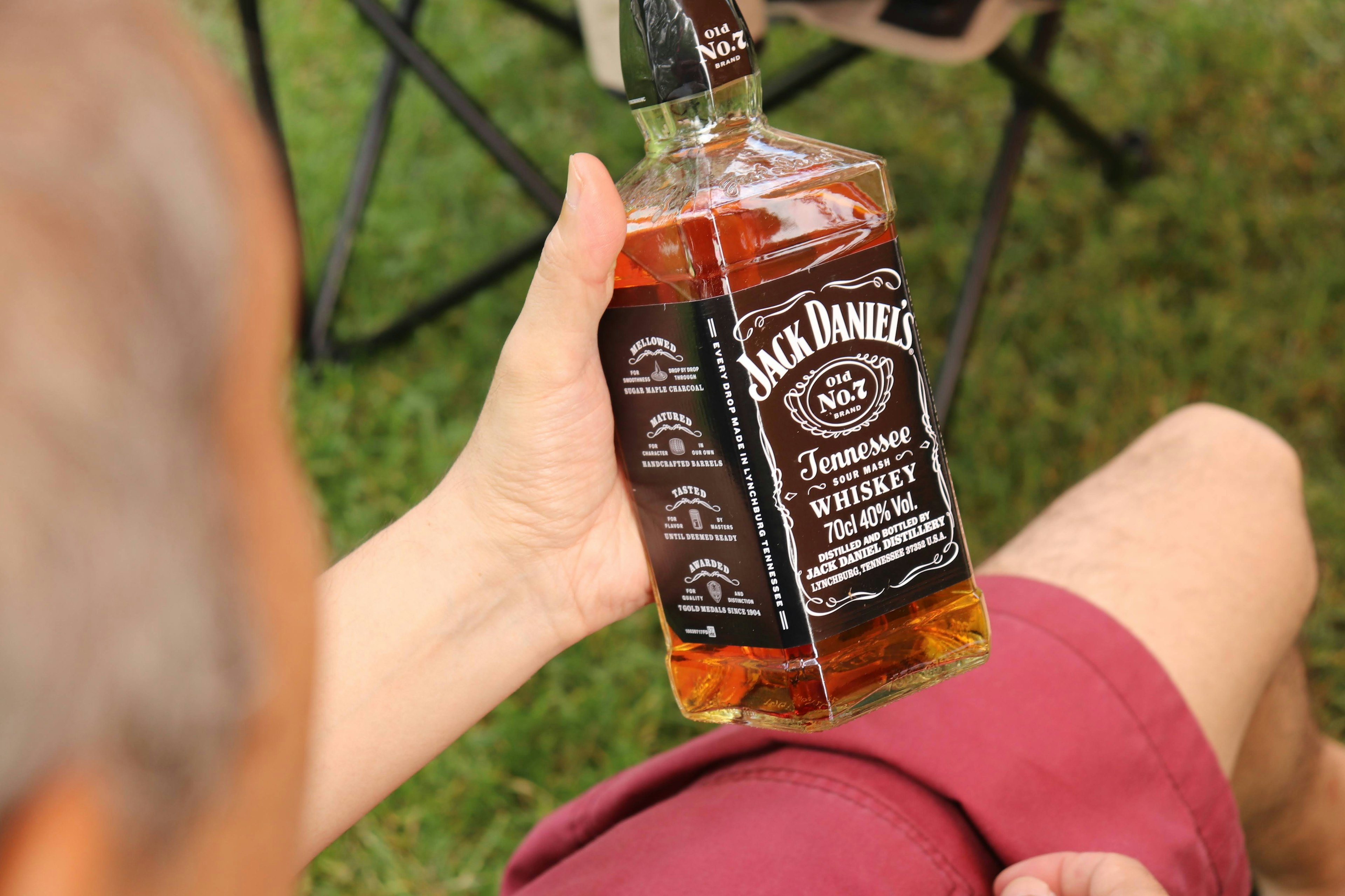 Orang yang memegang botol whisky Jack Daniel's