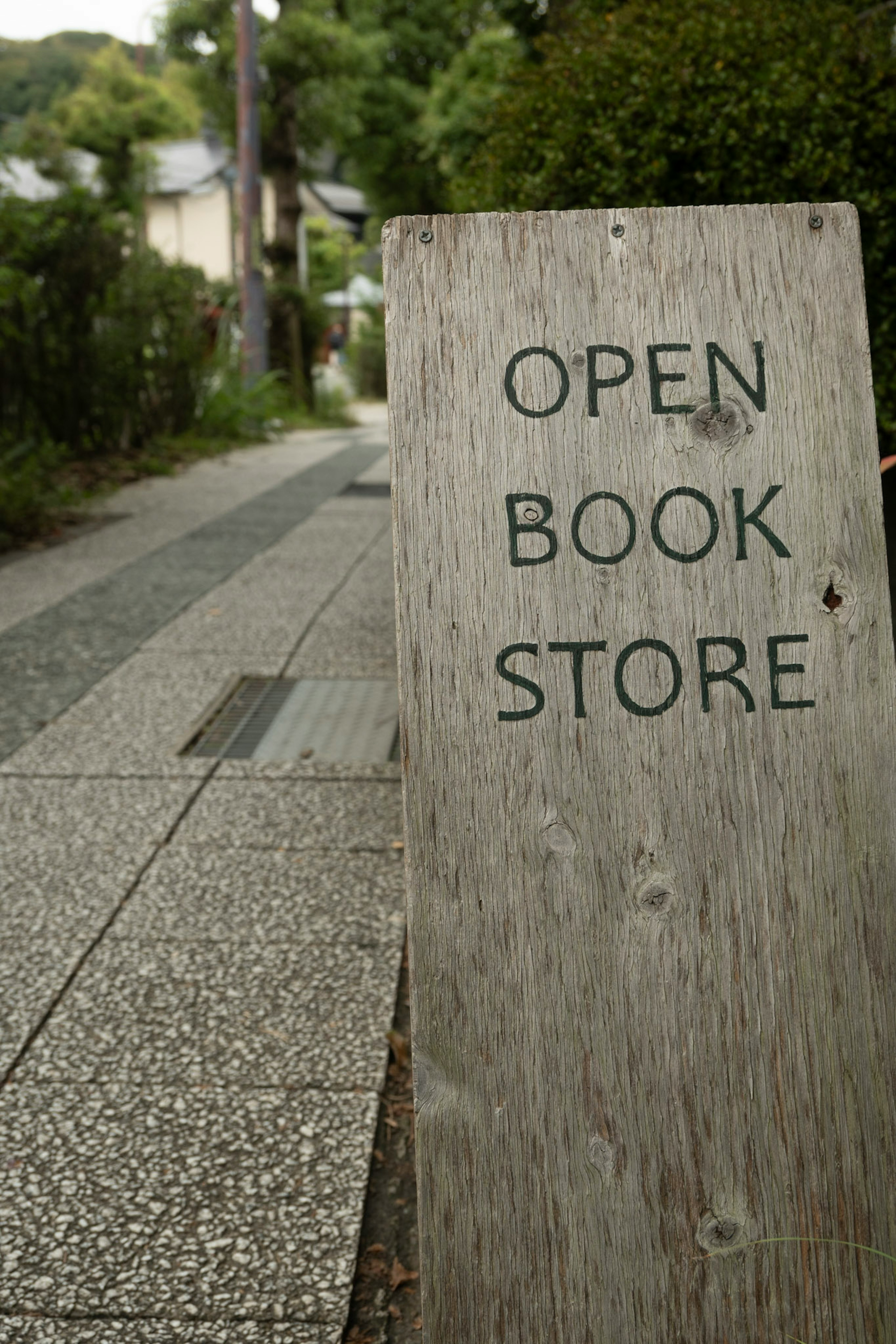 Wooden sign indicating open book store on a quiet street