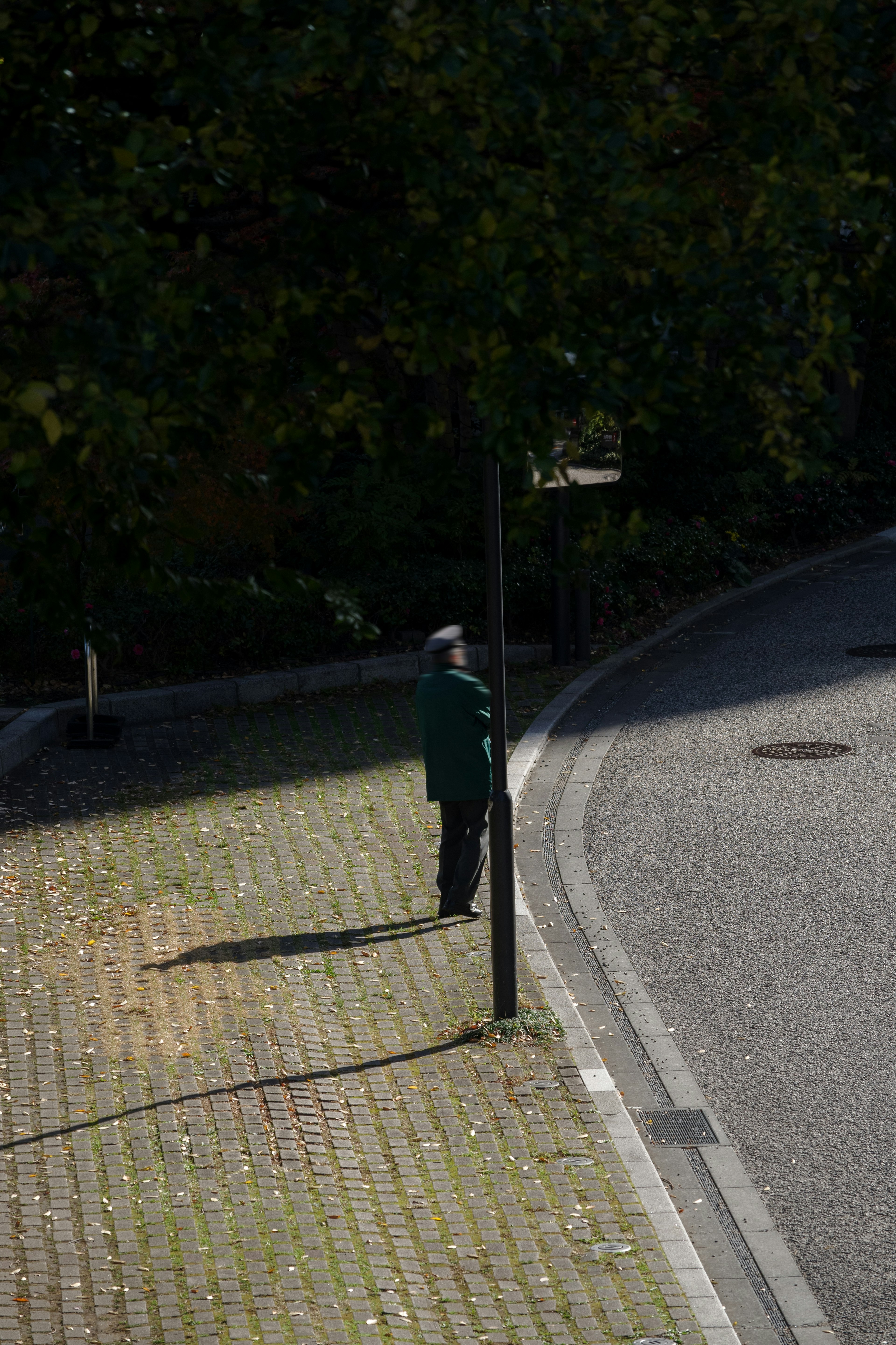 Eine Person steht an einer Straßenecke neben einem Laternenpfahl