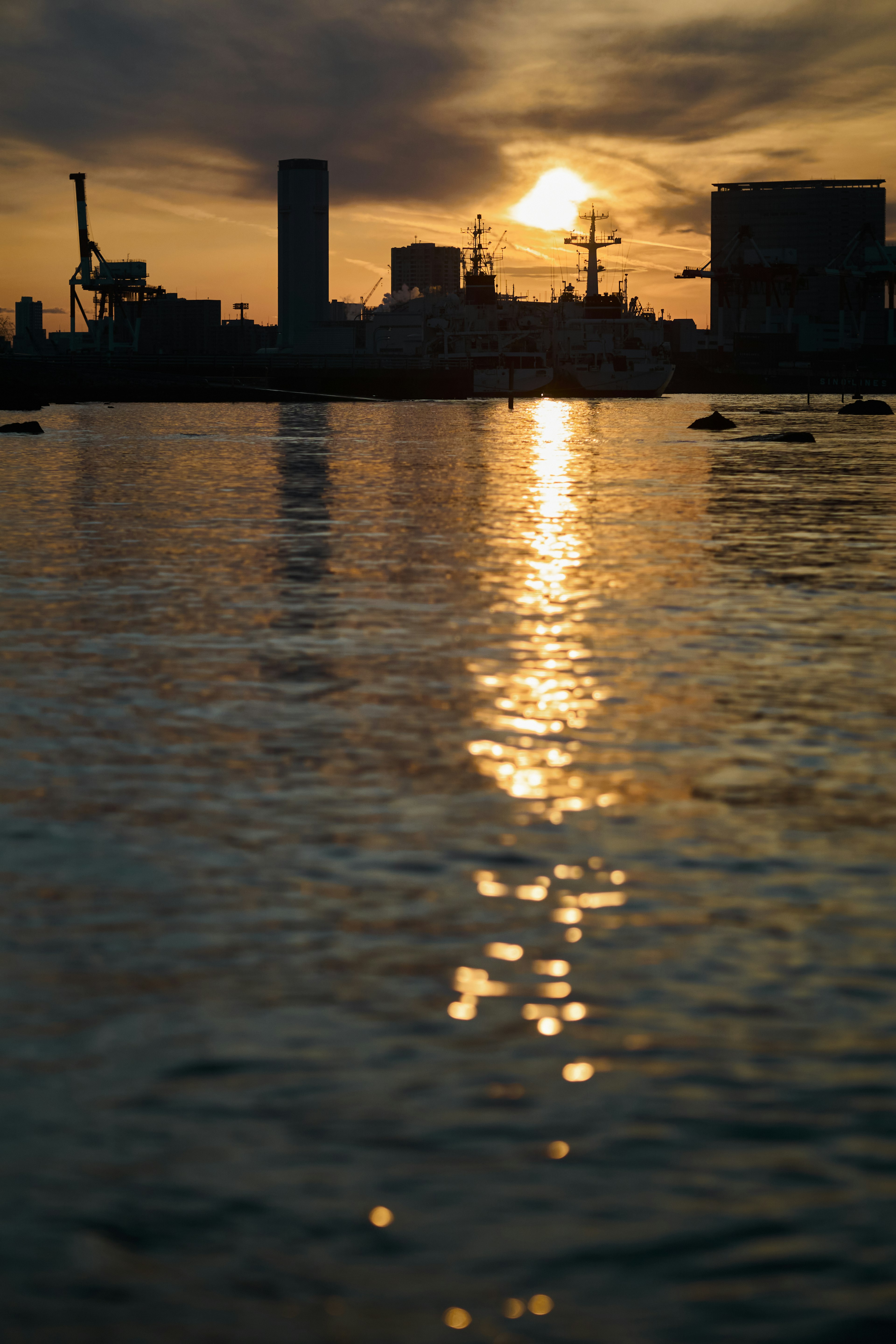 Coucher de soleil se reflétant sur l'eau avec un skyline de ville en silhouette