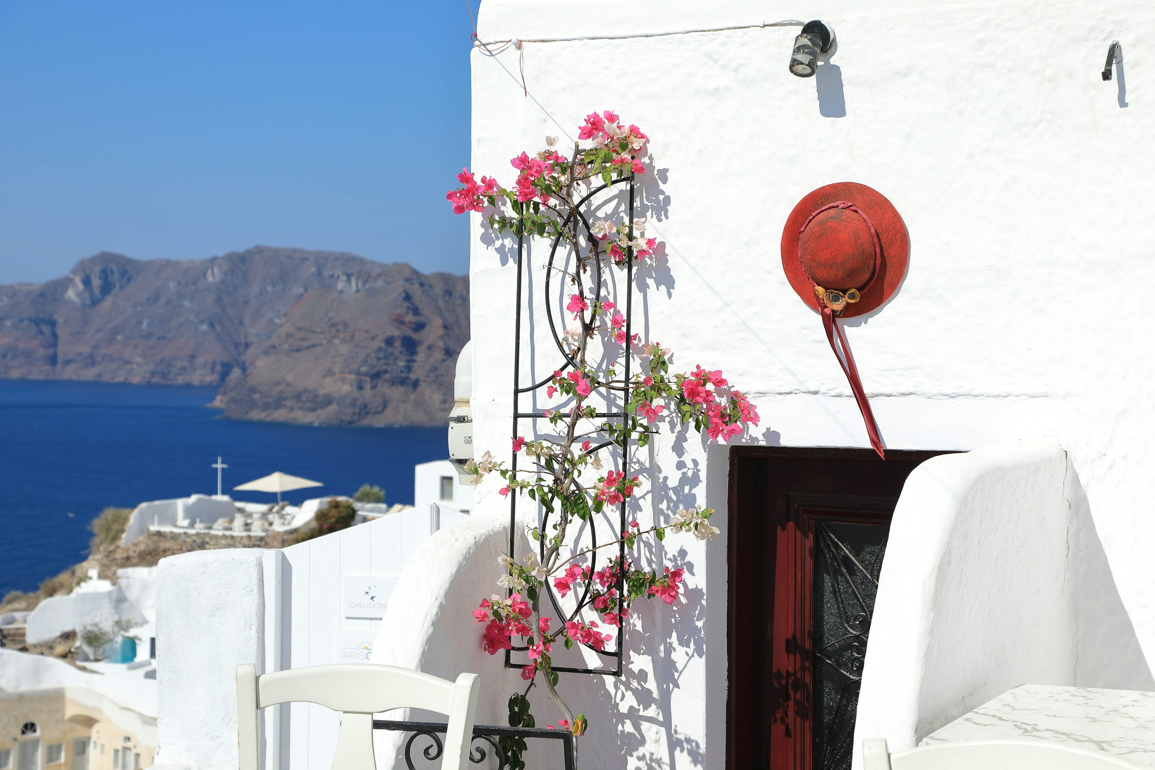 Hermosa vista de una casa blanca decorada con flores rosas y mar azul