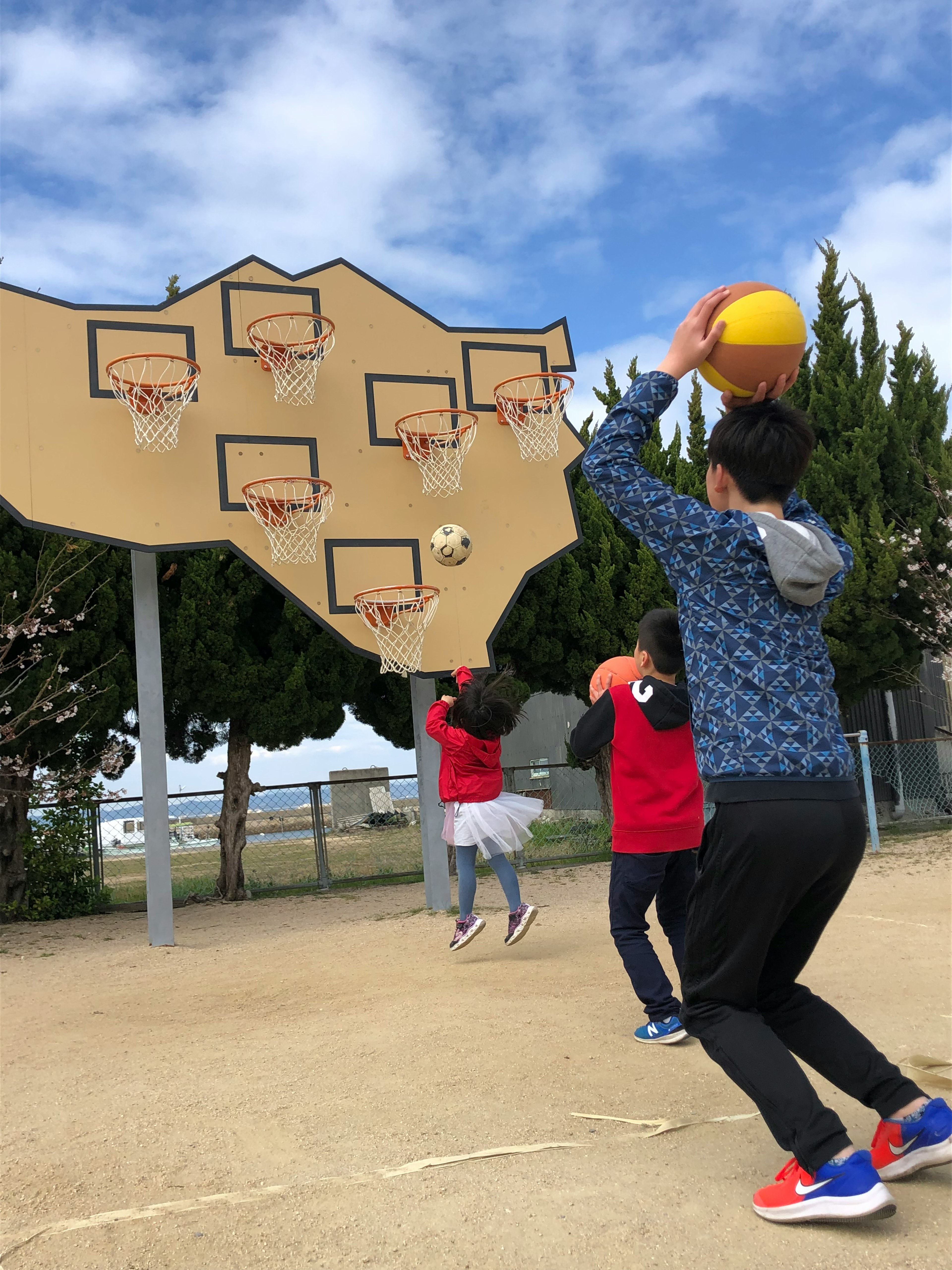 バスケットボールを投げる子供たちのグループがいる公園のシーン