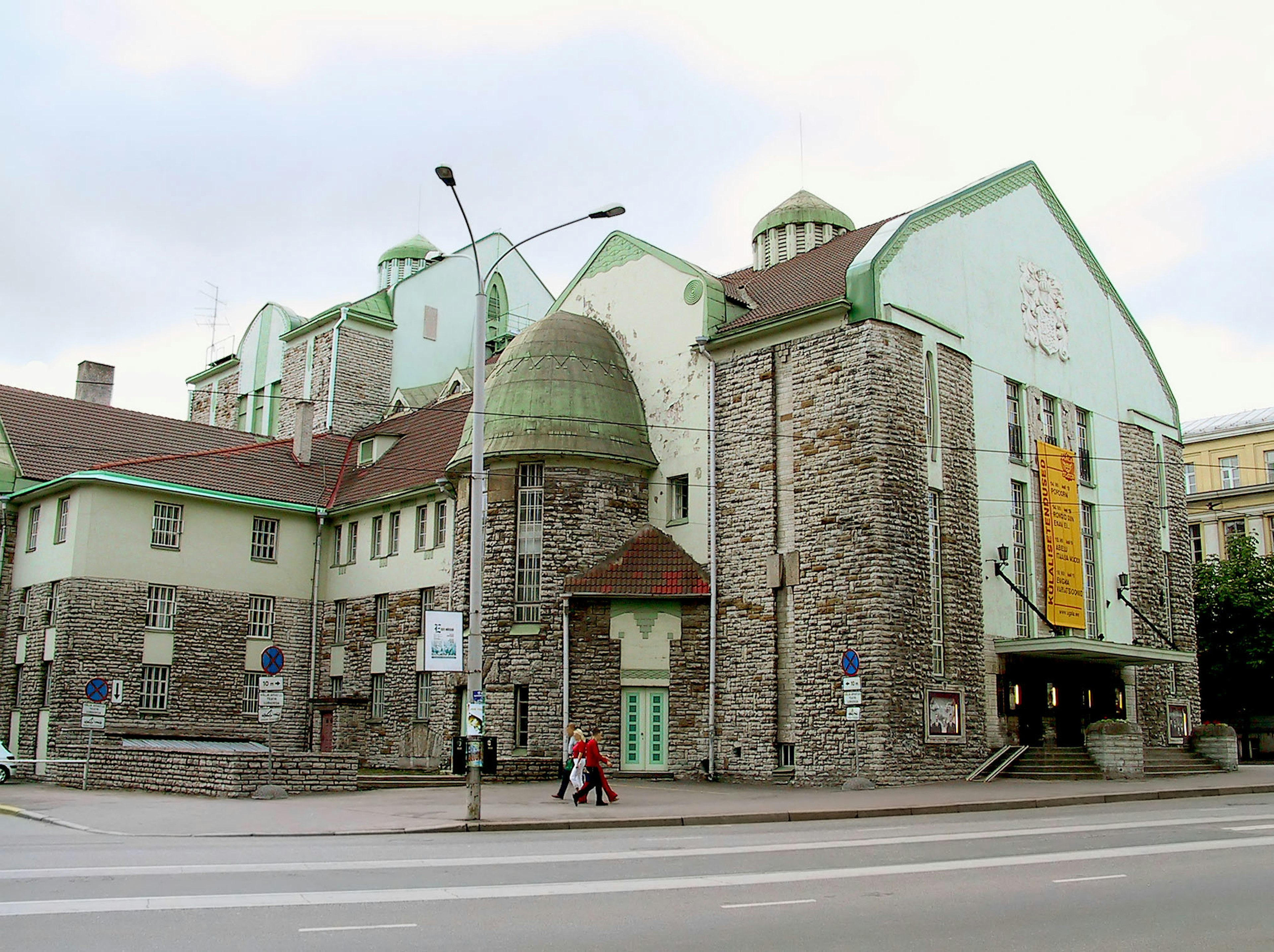 Exterior de un edificio de piedra con techos verdes y una pancarta de museo de arte