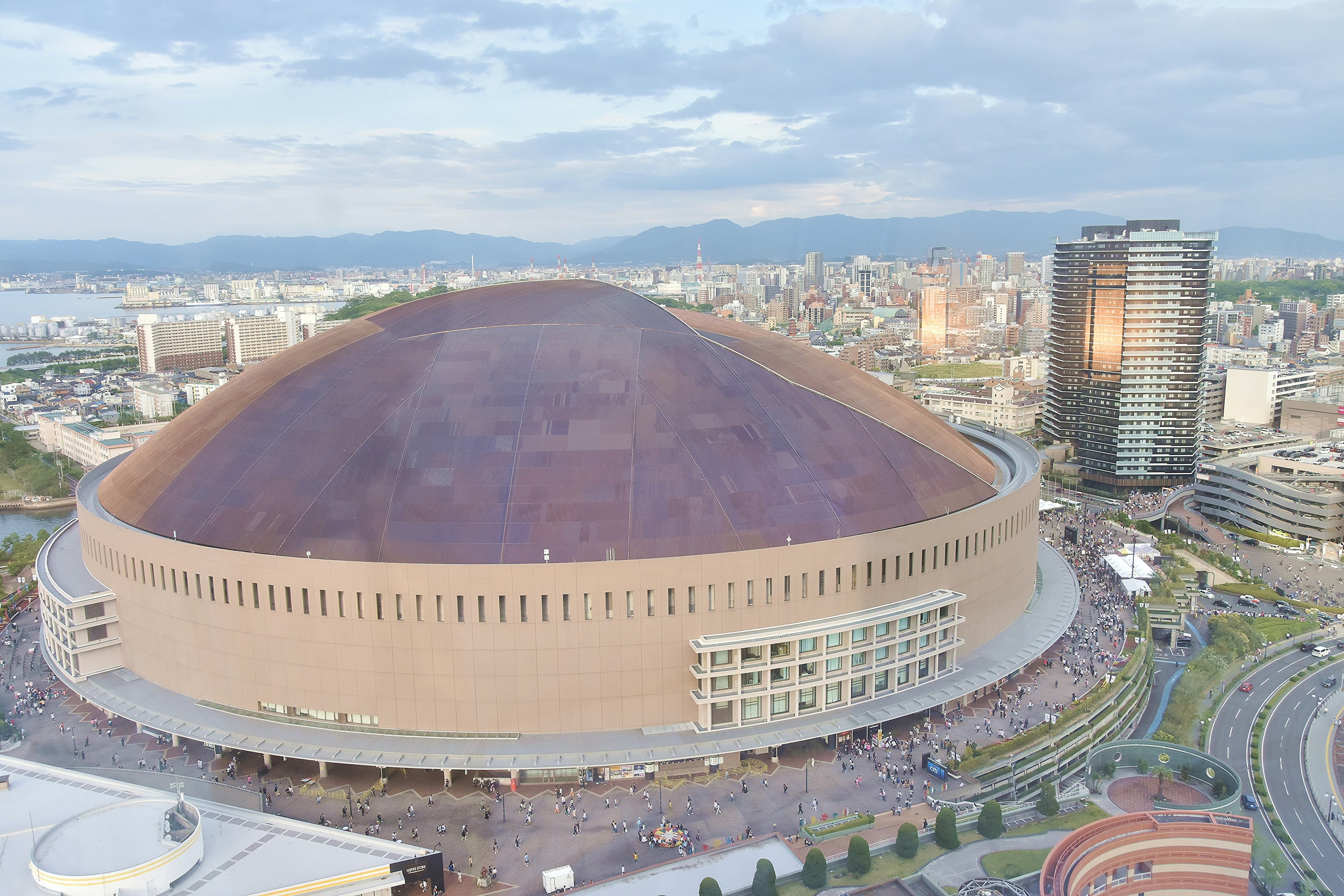 Großes kuppelförmiges Stadion mit umliegender Stadtlandschaft