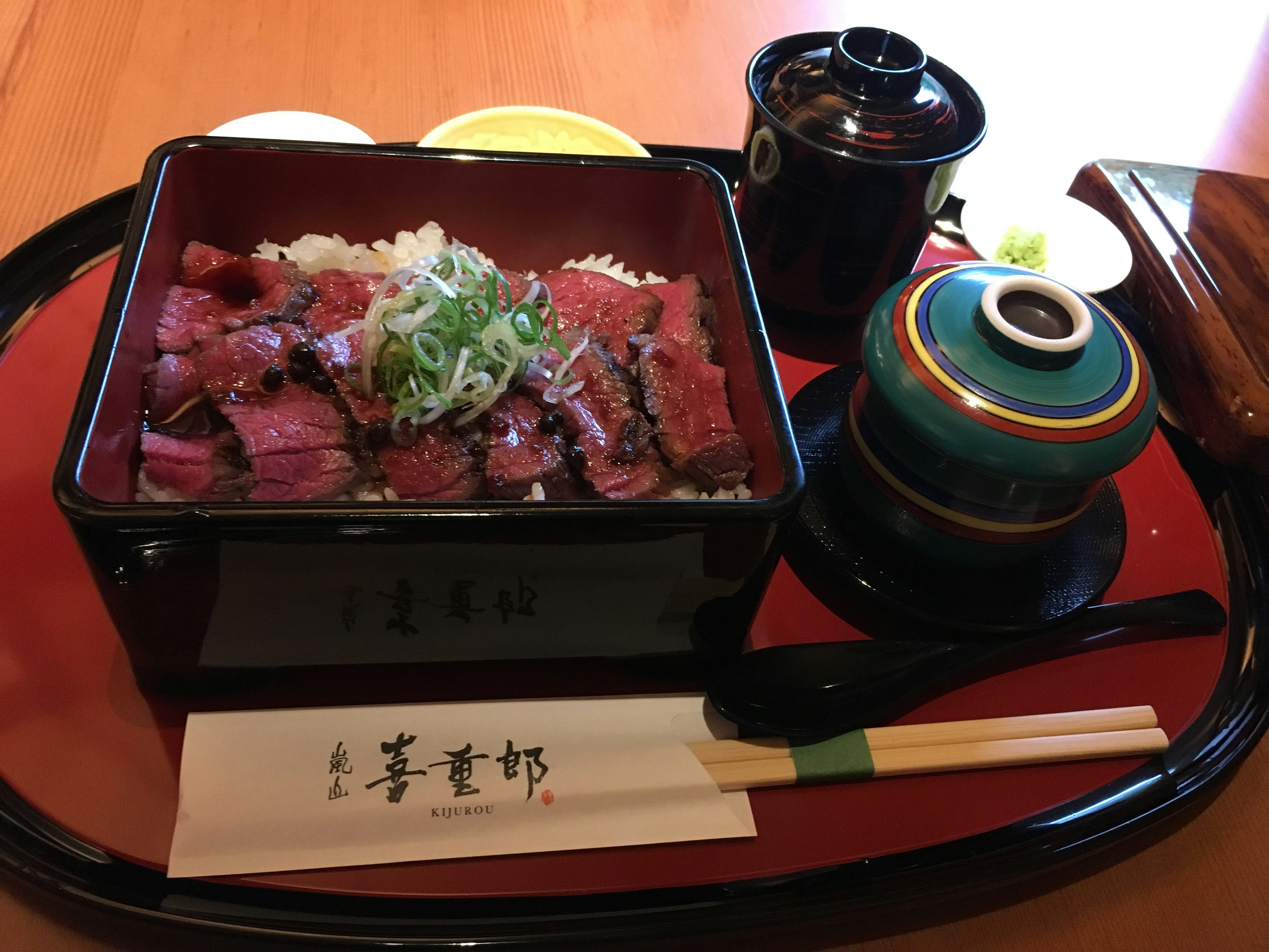 Plat de riz et viande dans une boîte noire garni d'oignons verts avec un service à thé