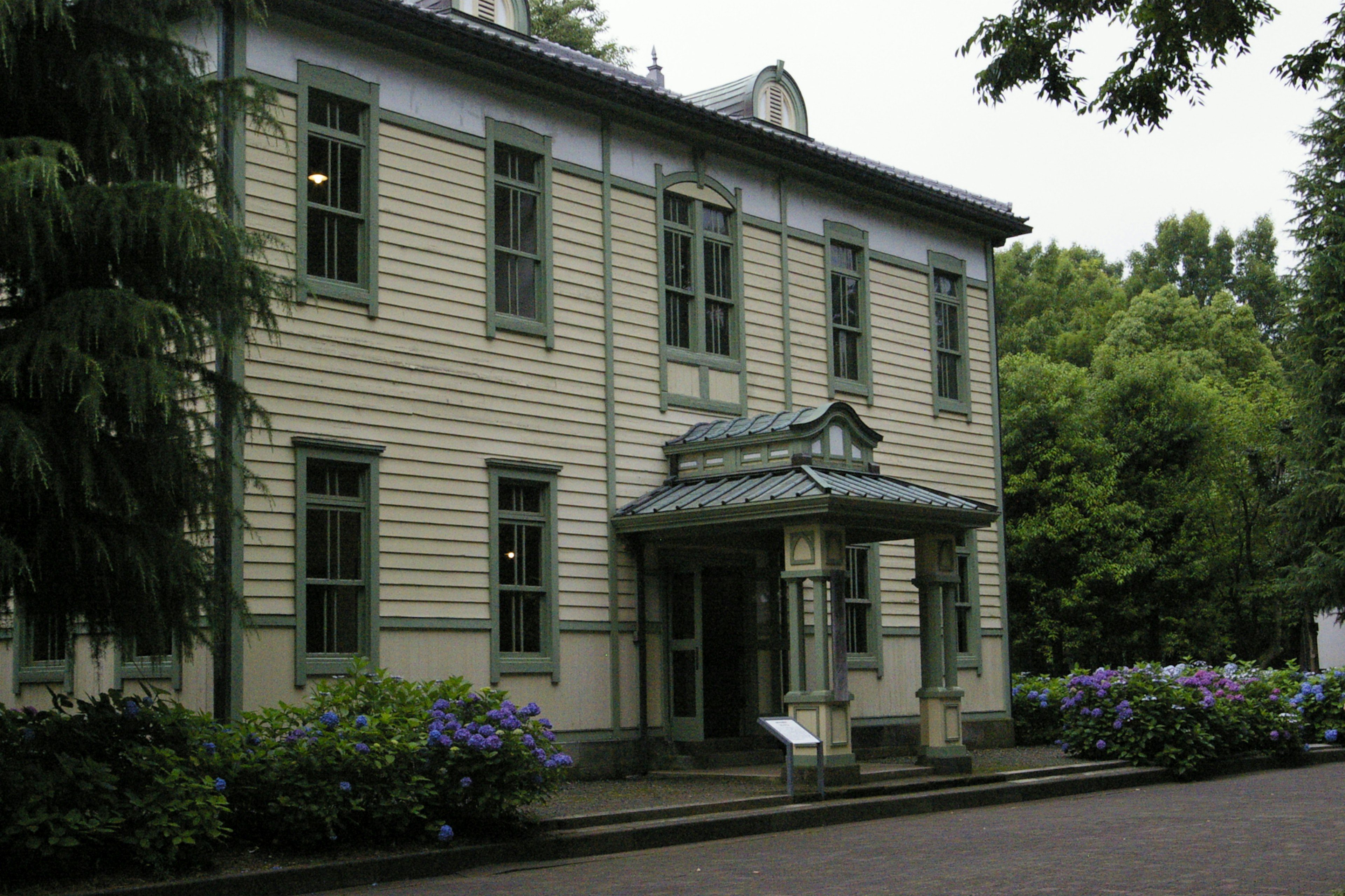 Façade d'un bâtiment historique avec des cadres de fenêtres verts et un toit décoratif