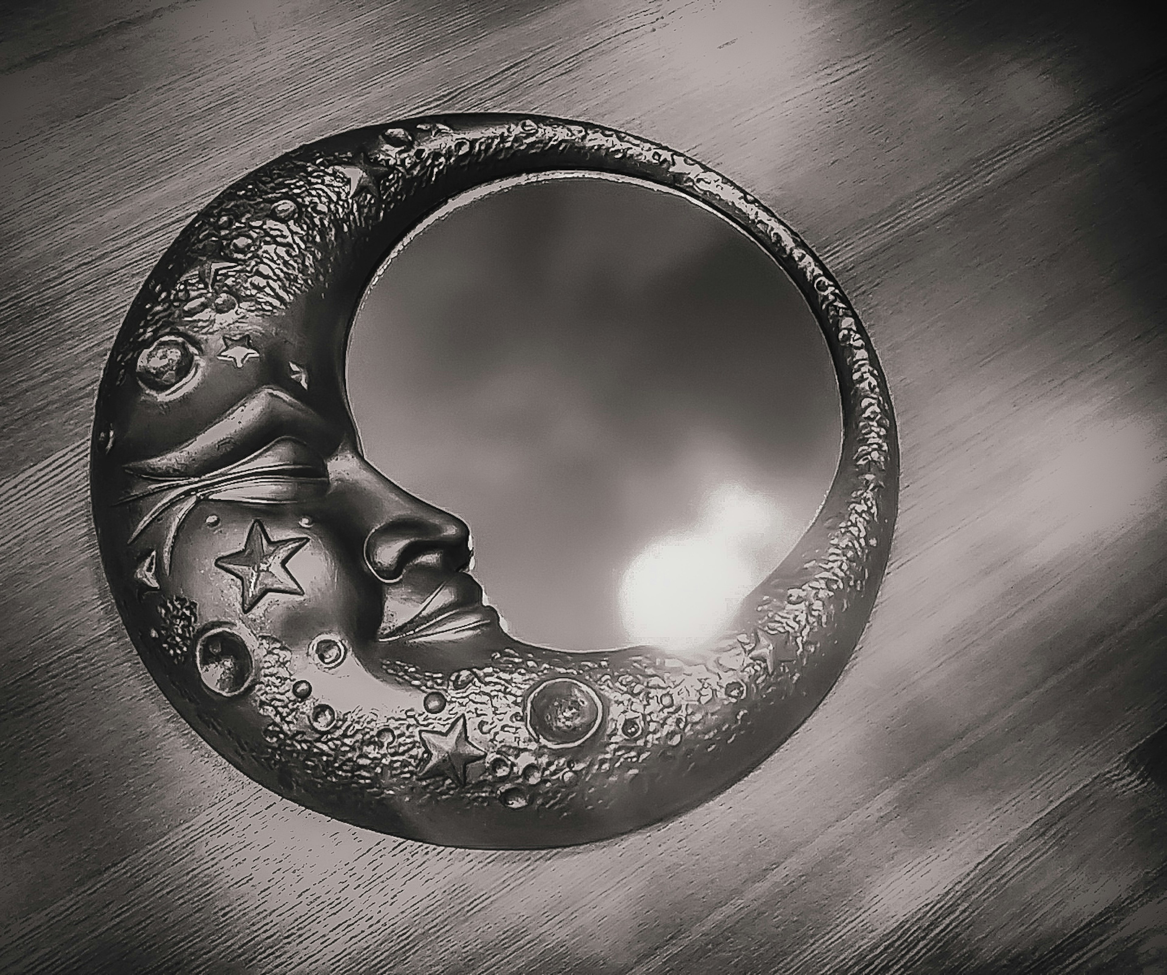 Moon-shaped mirror with decorative stars and intricate face features