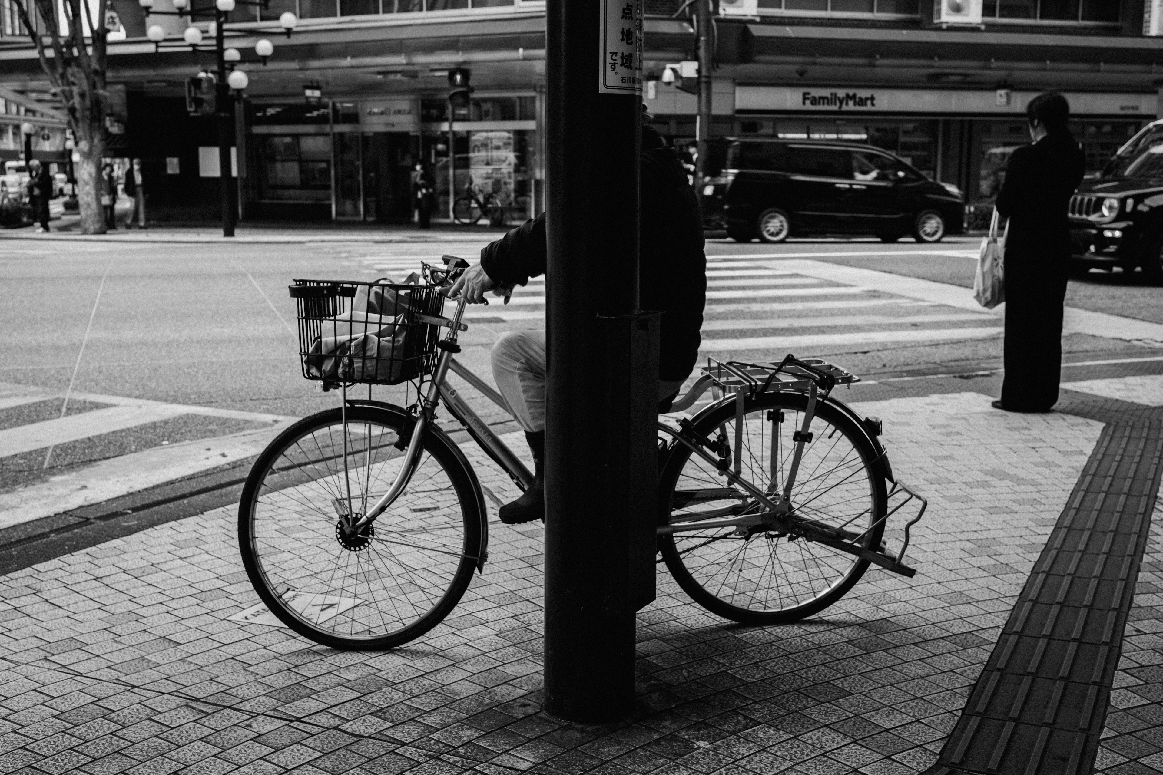 Black and white street scene with a bicycle leaning against a pole