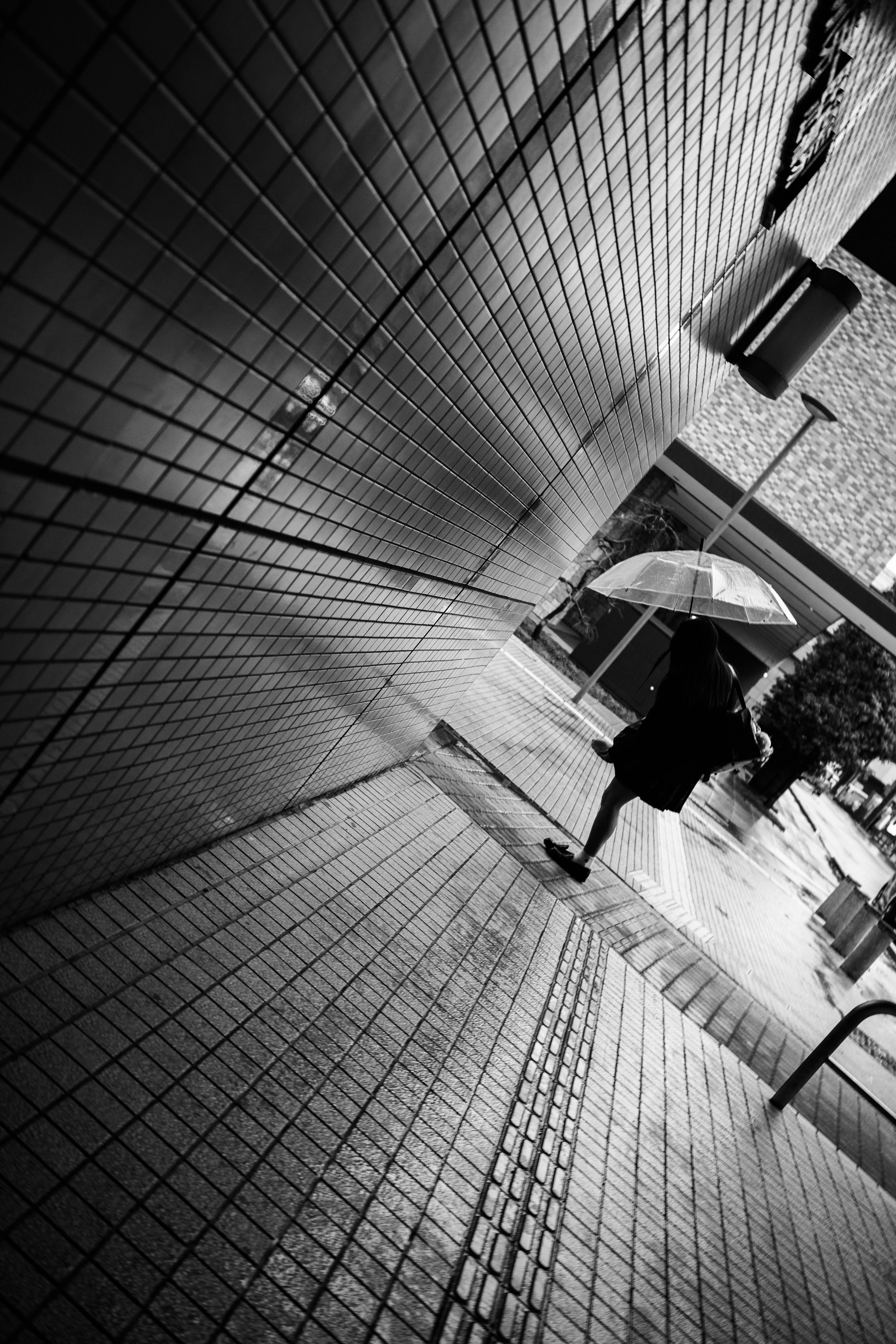 Silhouette of a person walking with an umbrella in a black and white corridor