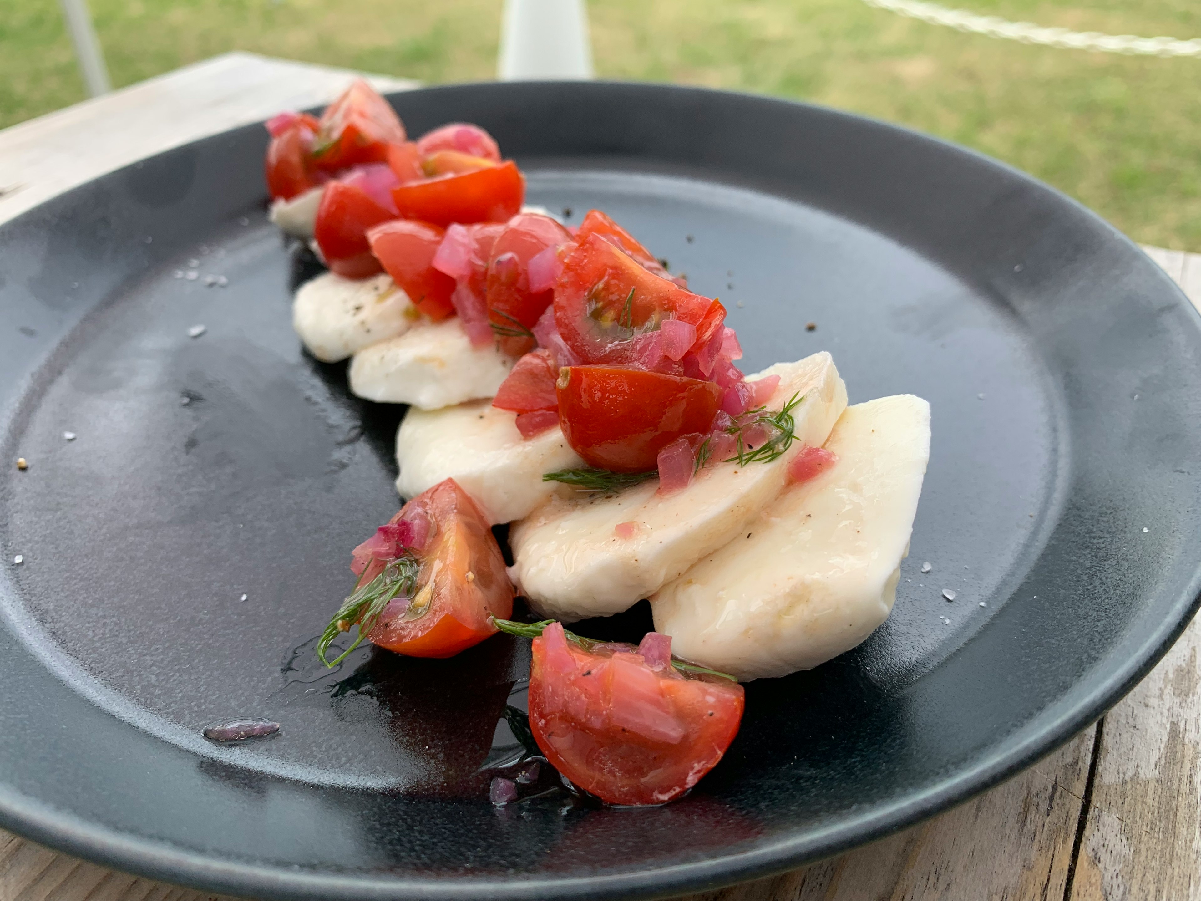 Pisang yang diiris dengan salsa tomat segar di atas piring hitam