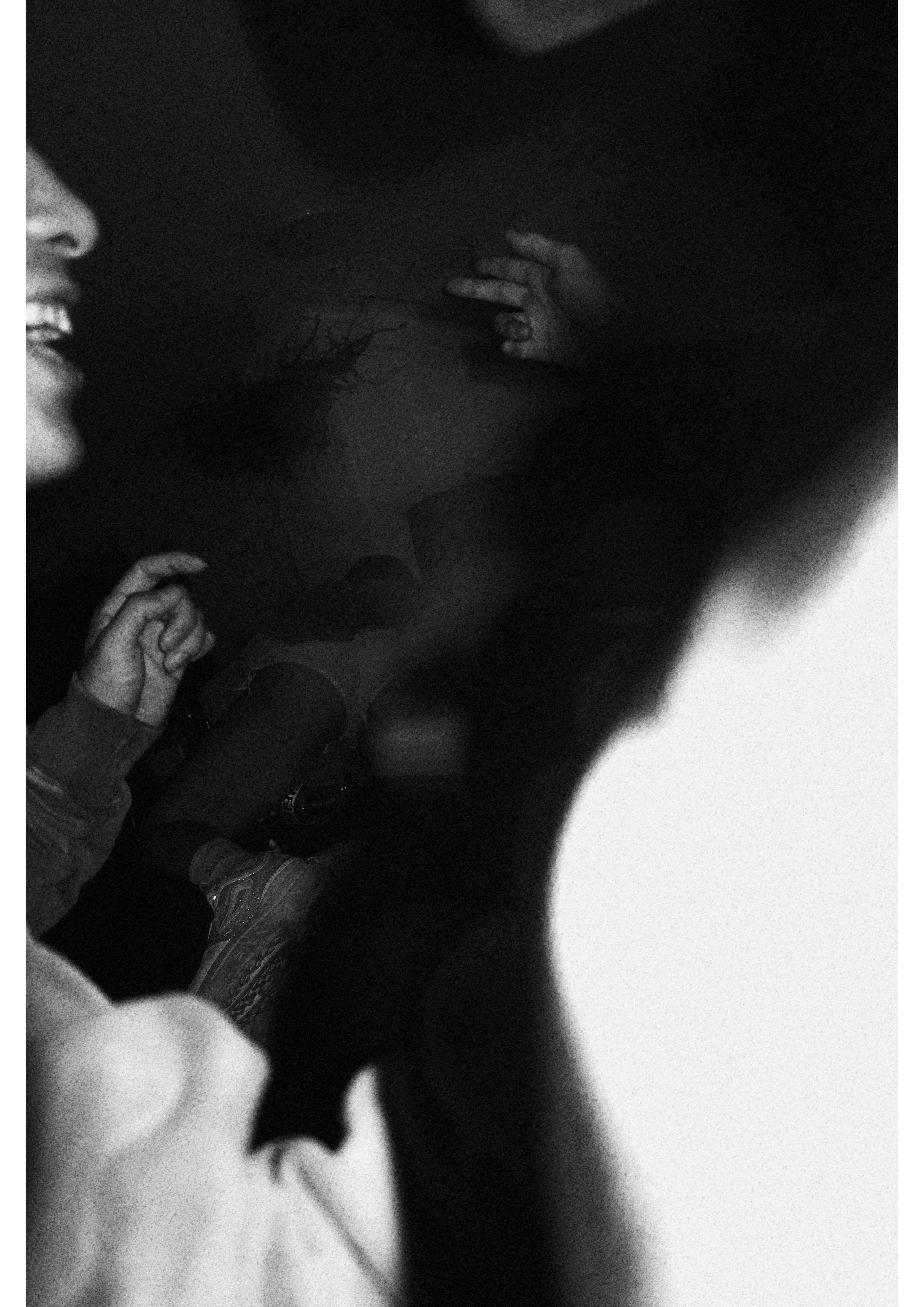 Imagen en blanco y negro que muestra a una persona sonriendo y manos sobre un fondo oscuro