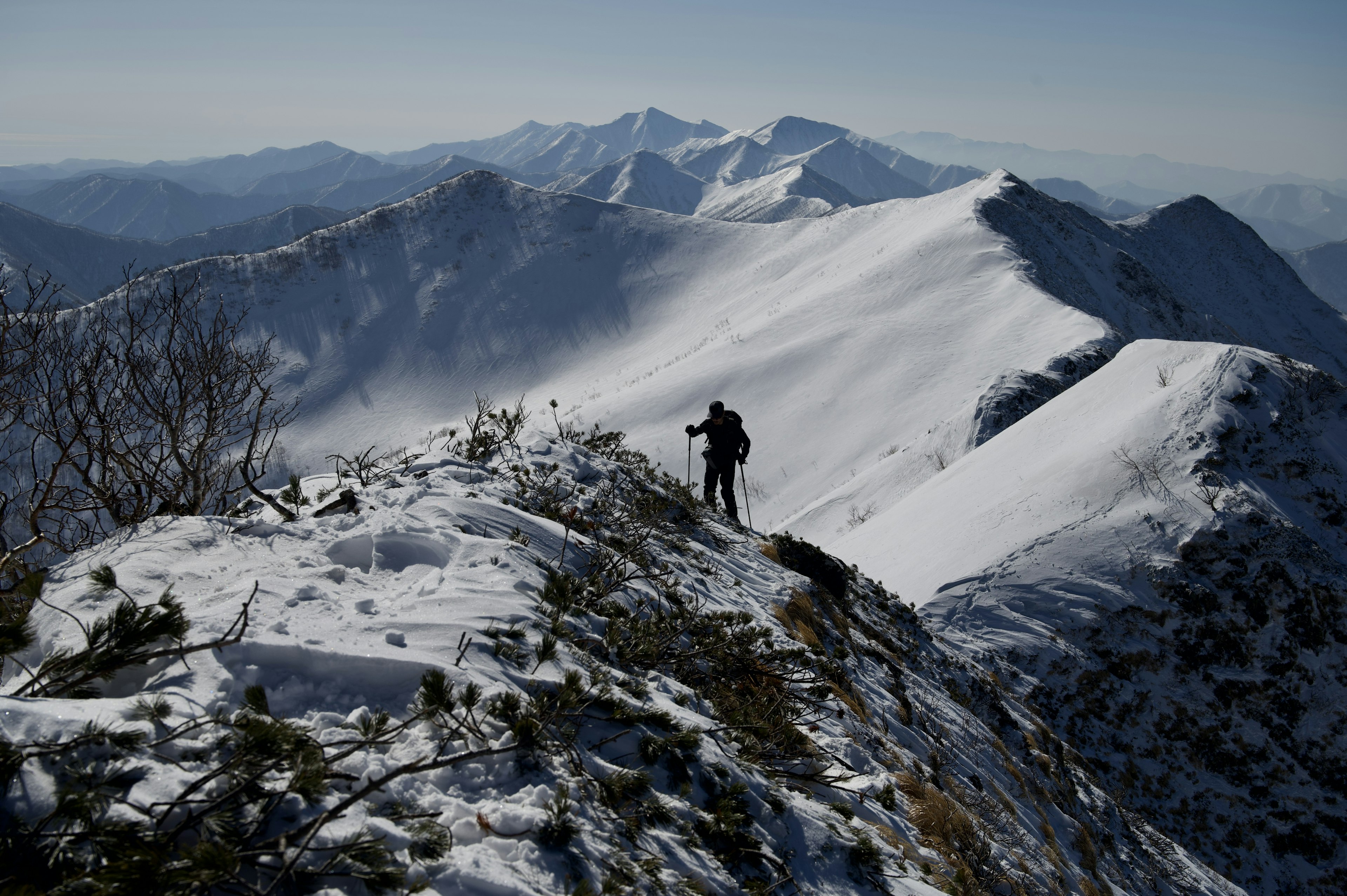 Silhouette of a hiker walking on a snow-covered mountain ridge