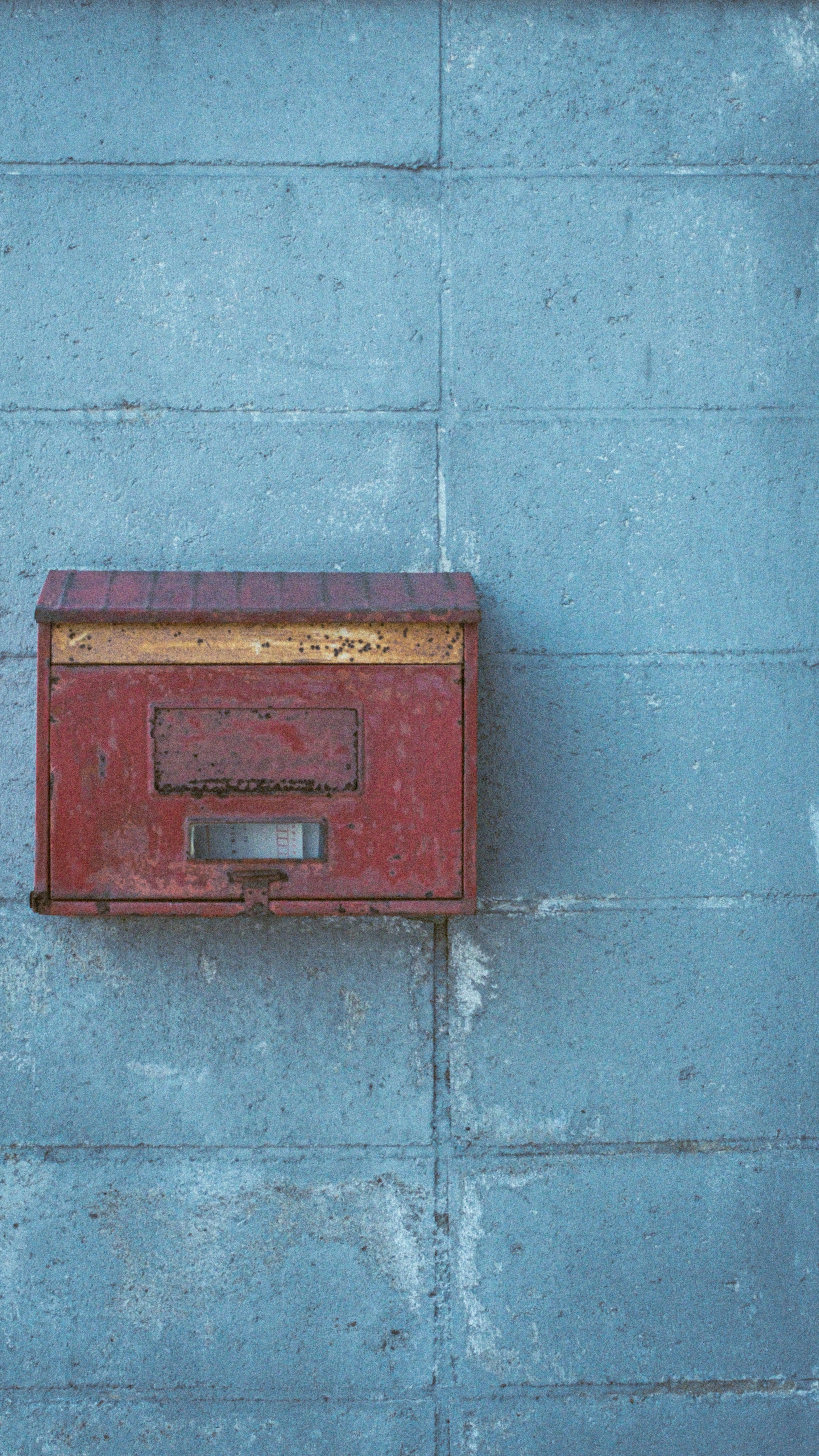 Red mailbox mounted on a blue wall