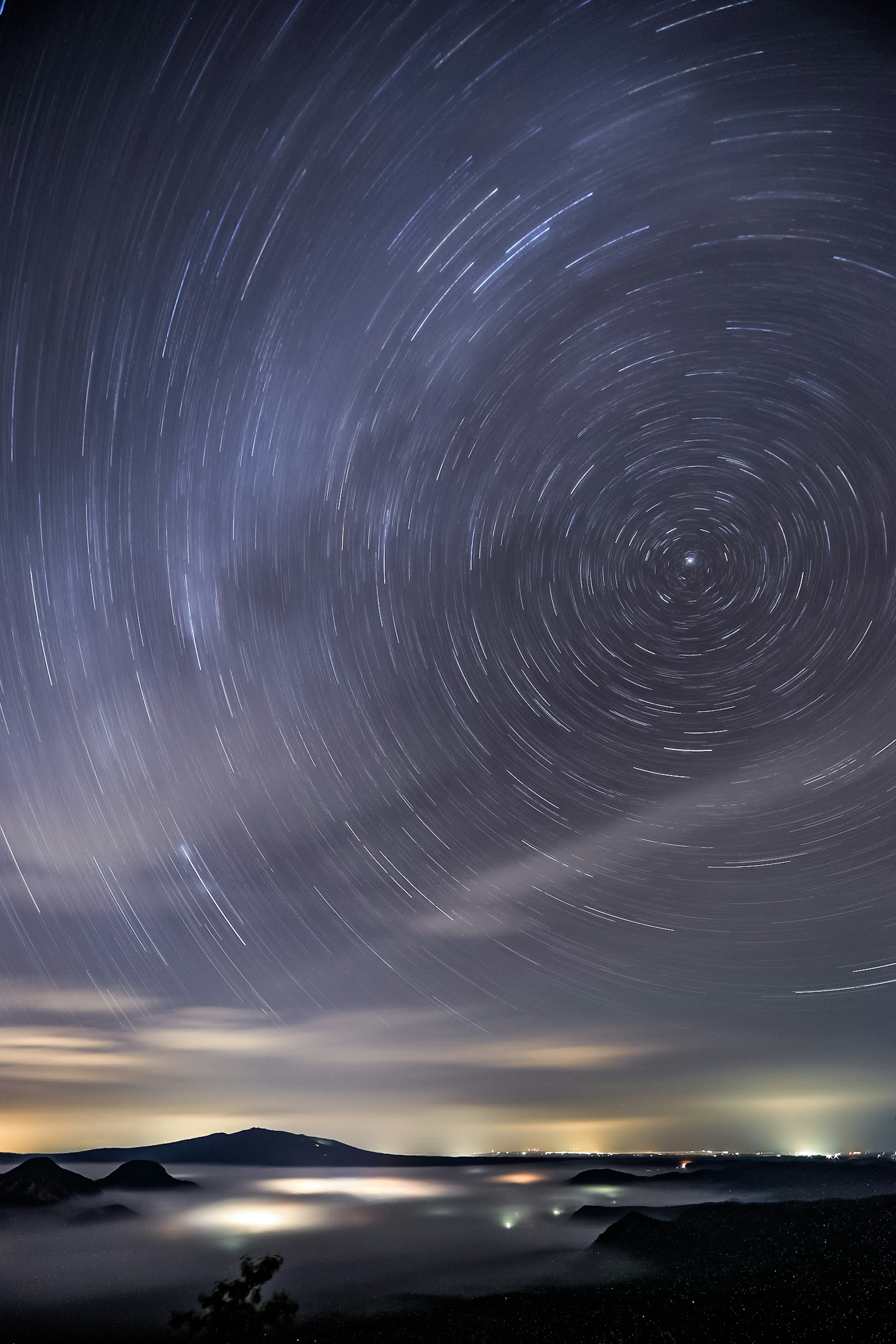 星の軌跡が描かれた夜空の写真山々と雲が背景にある